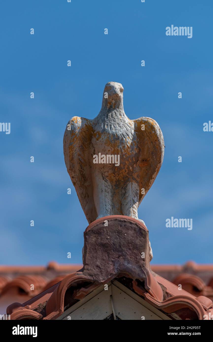 pietra aquila statuario giardino tetto tegola, ornamenti giardino, giardinaggio, statuario, statue, ornamenti in pietra, aquila in pietra sul colmo del tetto. Foto Stock