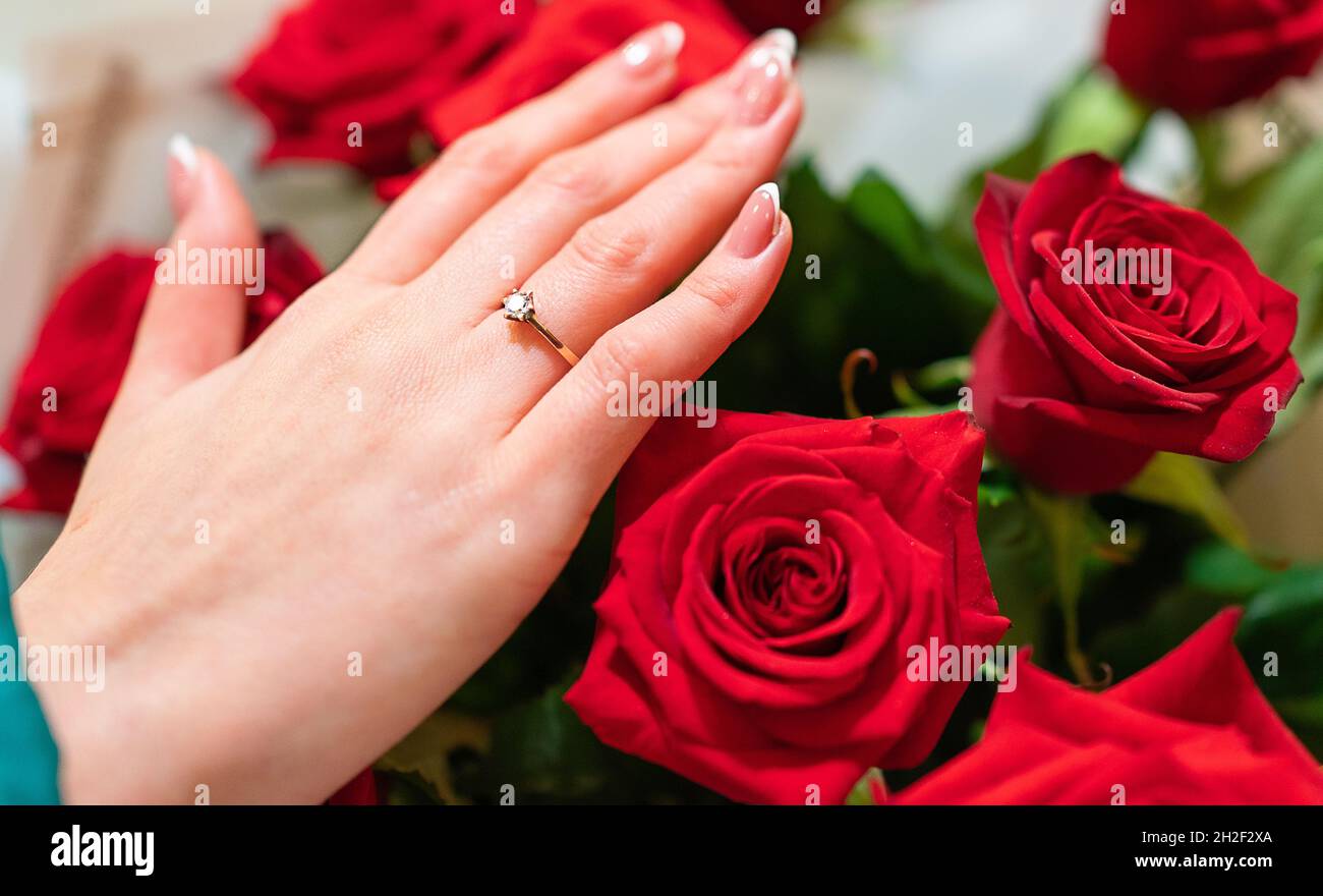 Mano femmina con anello di aggancio su un mazzo di rose rosse Foto stock -  Alamy