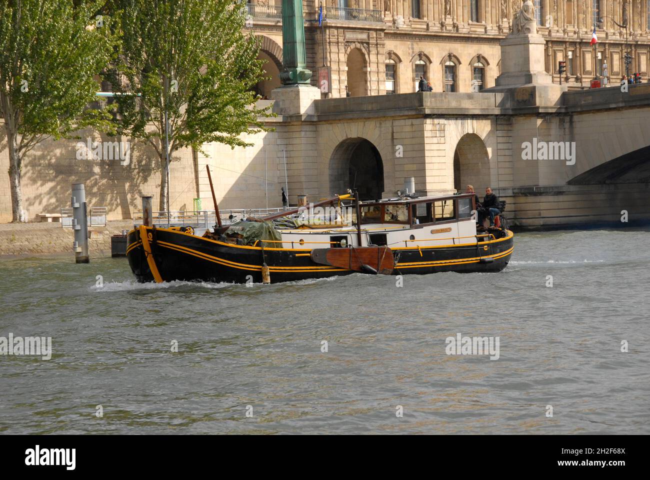 Barca commerciale sul fiume Senna, Parigi, Francia con due persone sedute a poppa Foto Stock
