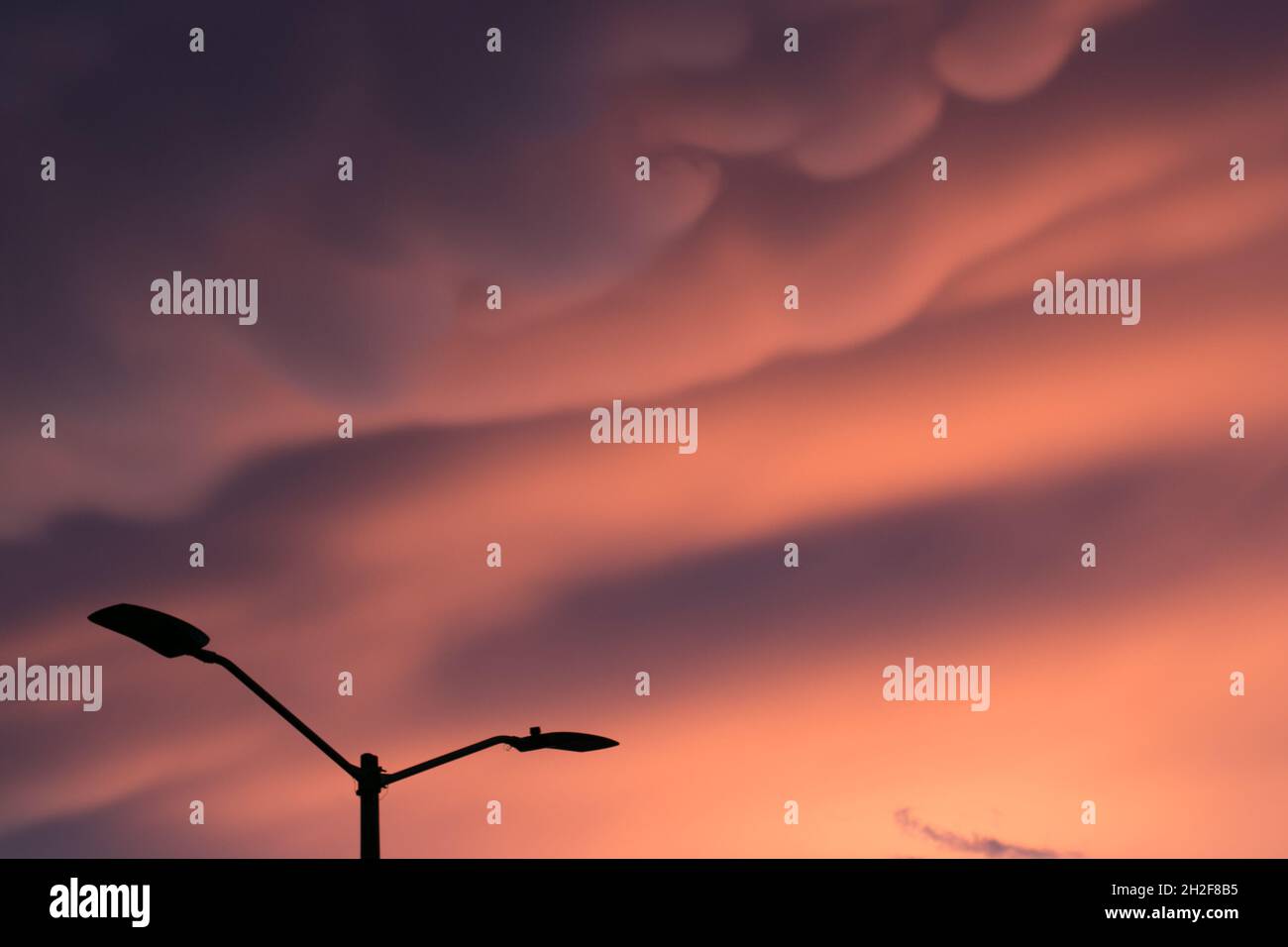 Silhouette con lampione di fronte a un incredibile tramonto in città con nuvole di caramelle in cotone Foto Stock