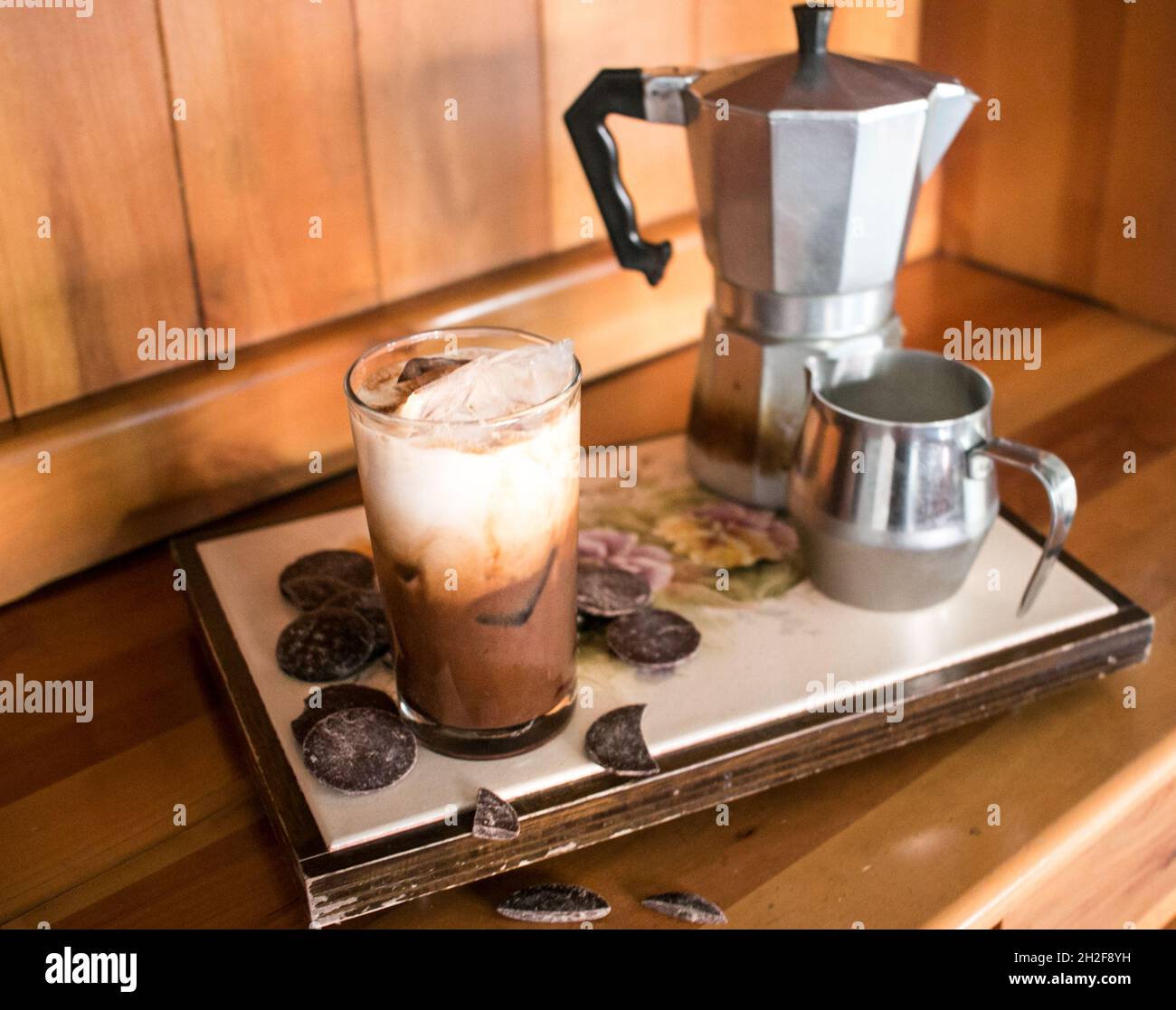 Pronto a bere delizioso caffè ghiacciato al cioccolato su vassoio con cioccolato, eleganti vibrazioni in legno Foto Stock