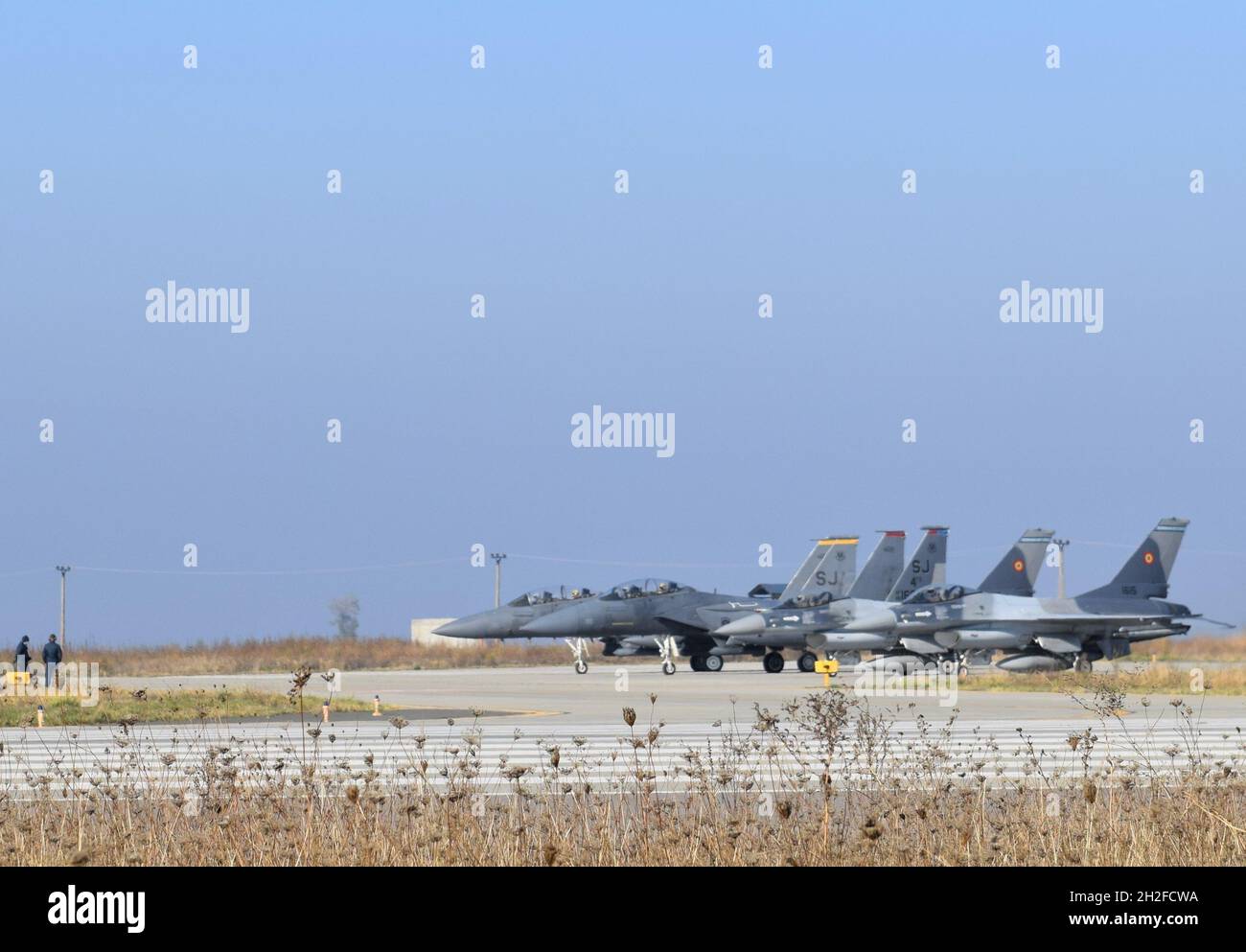 F-16 Rumeno Fighting Falcon Aircraft taxi accanto agli US F-15E Sciopero aquile dal 336th Fighter Squadron, 4th Fighter Wing, Seymour Johnson Air Force base, North Carolina, durante la seconda settimana di operazione Castle Forge alla base aerea di Balcea, Romania, 20 ottobre 2021. Castle Forge simula tattiche di dispiegamento e dispersione per le unità dell'Aeronautica militare degli Stati Uniti mentre si allenano insieme alle controparti dell'Aeronautica greca, bulgara e rumena (U.S.A. Air Force foto di Capt. Andrew Layton). Foto Stock