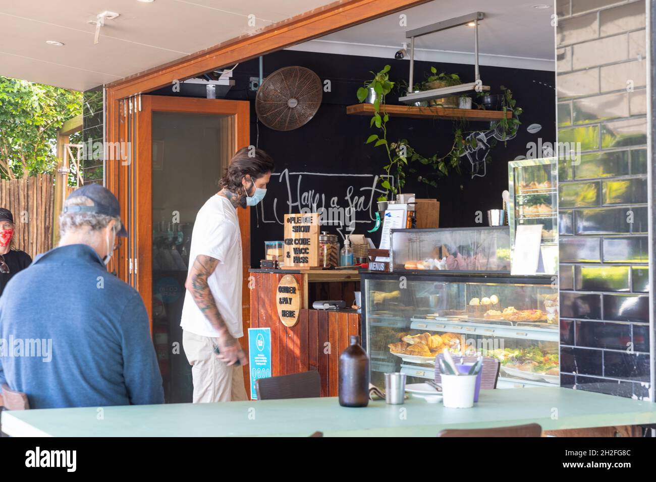 Sydney, Australia uomo che indossa un facemark a causa di 19 pandemic mette ordine di caffè in un caffè di Sydney che indossa il facemark, Australia Foto Stock