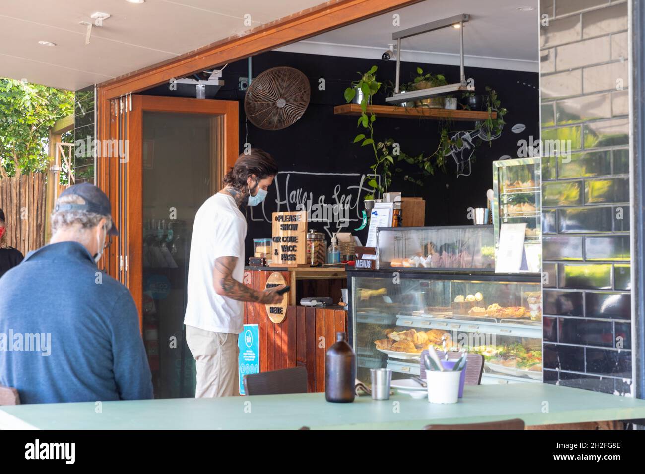 Sydney, Australia uomo che indossa un facemark a causa di 19 pandemic mette ordine di caffè in un caffè di Sydney che indossa il facemark, Australia Foto Stock
