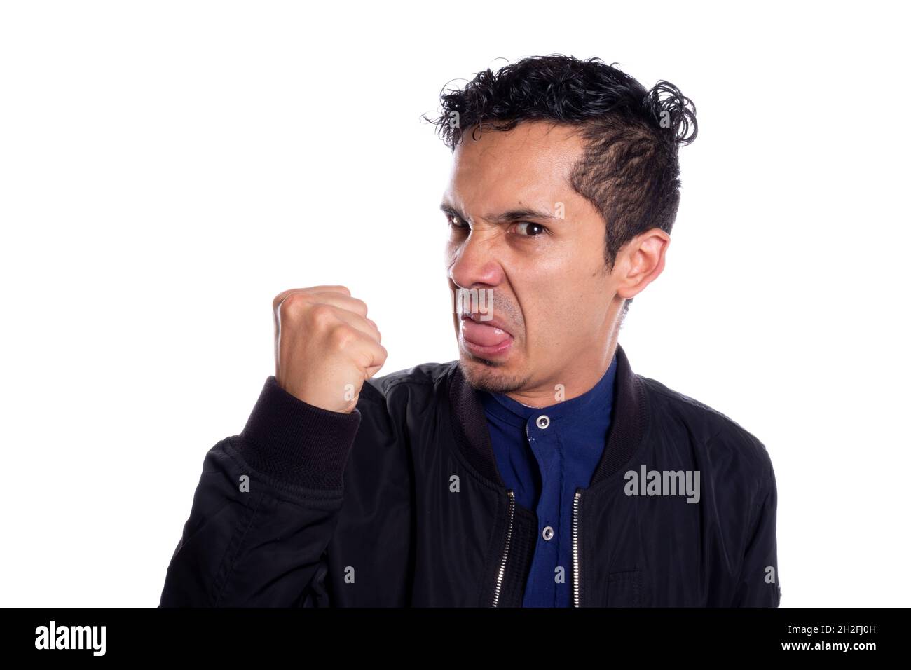Uomo arrabbiato con desiderio di colpire, su sfondo bianco. Giovane adulto latino grumpy giovane uomo che stringe il pugno a punch. Foto Stock