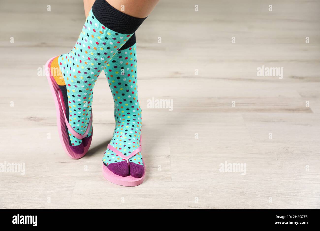 Donna che indossa calzini luminosi con infradito in piedi sul pavimento.  Spazio per il design Foto stock - Alamy