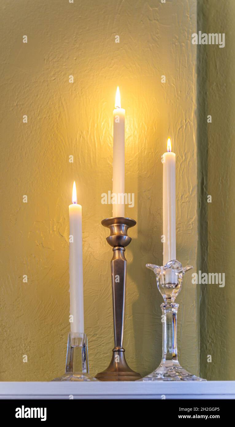 Tre candele illuminate in peltro & candele di cristallo sul mantello del camino, simbolo delle feste, romanticismo, giorno di San Valentino & uno stile di vita elegante. Foto Stock