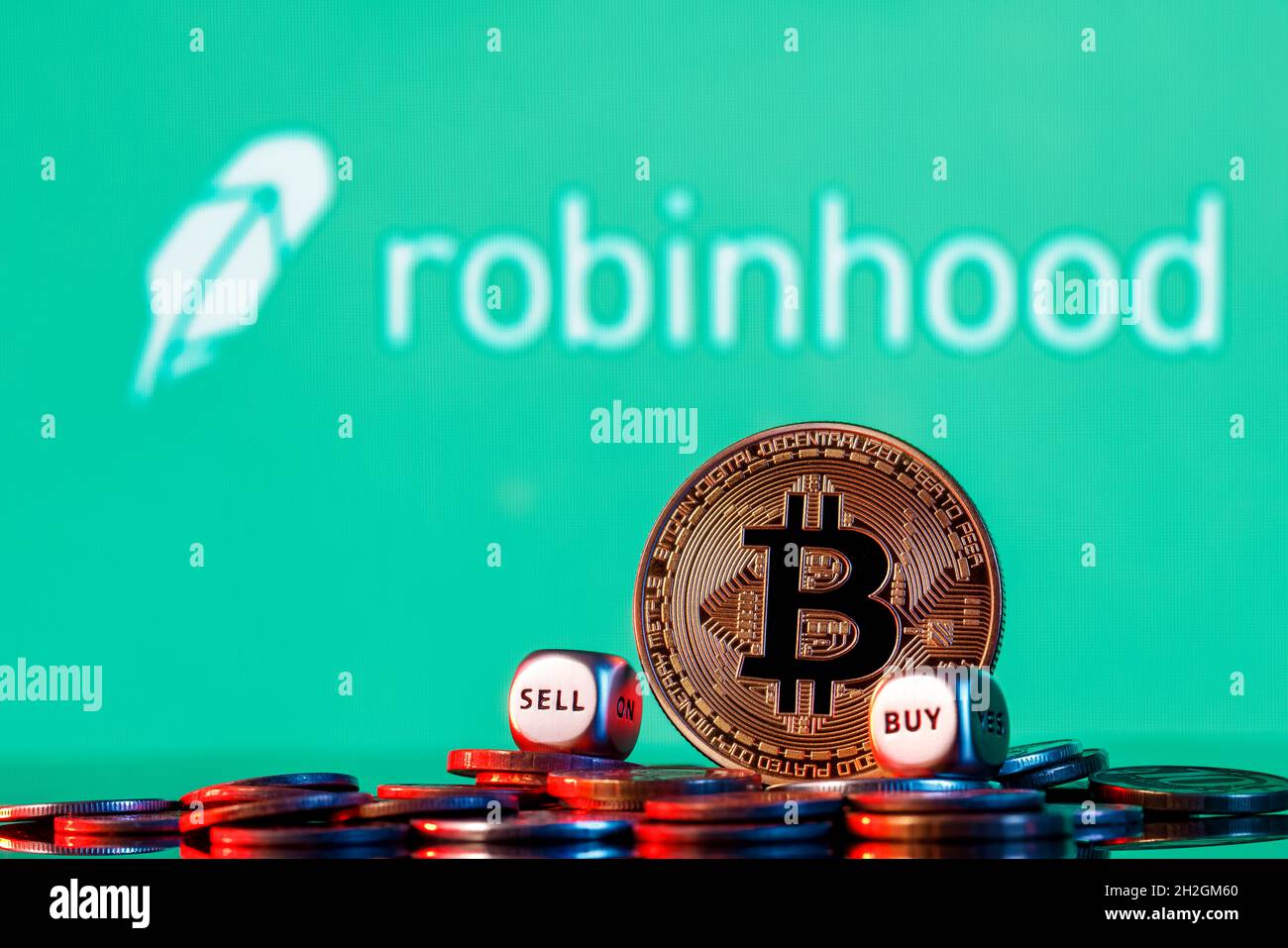 Bitrino d'oro con due cubetti buy-sell in un mucchio di monete sullo sfondo del logo Robinhood. Foto Stock