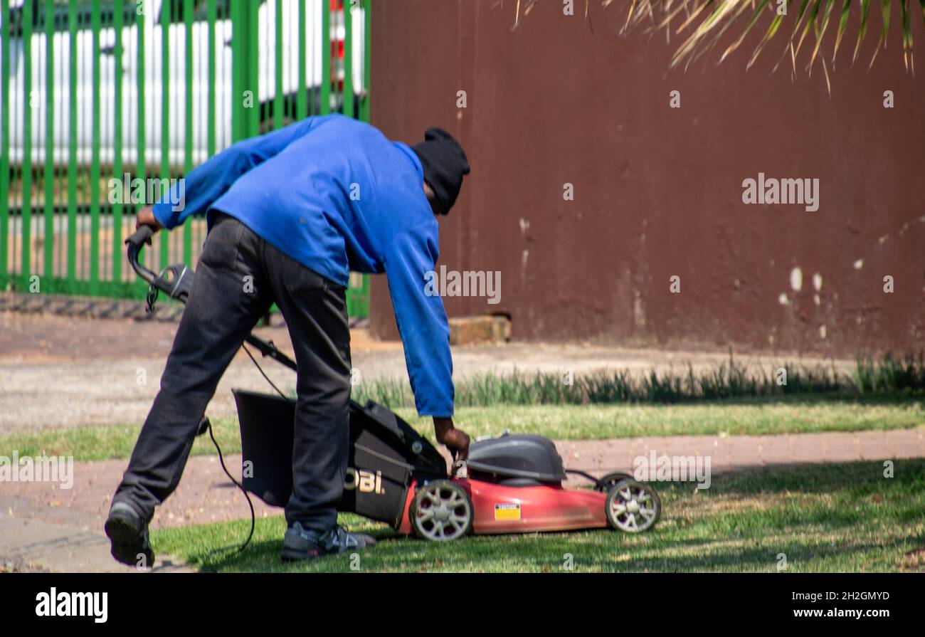 Johannesburg, Sudafrica - un uomo nero non identificato muove il prato in una proprietà residenziale Foto Stock