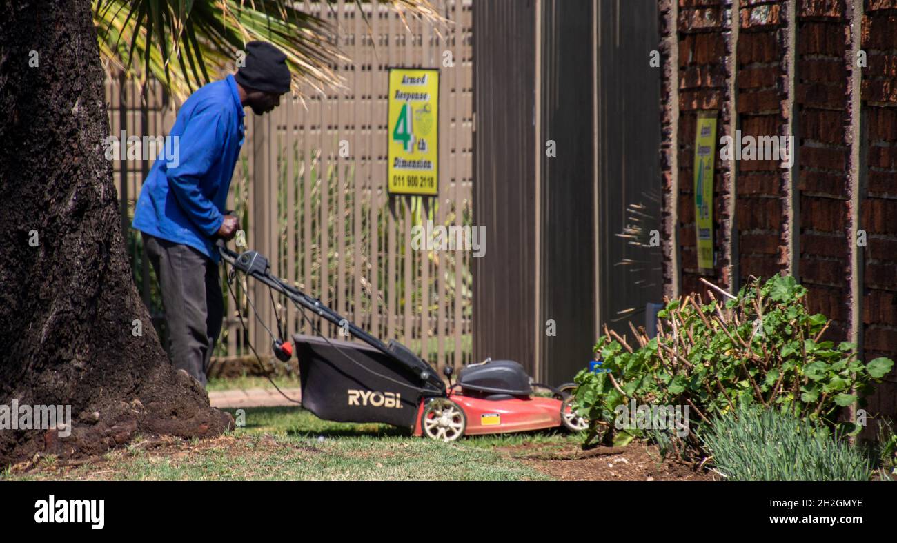 Johannesburg, Sudafrica - un uomo nero non identificato muove il prato in una proprietà residenziale Foto Stock