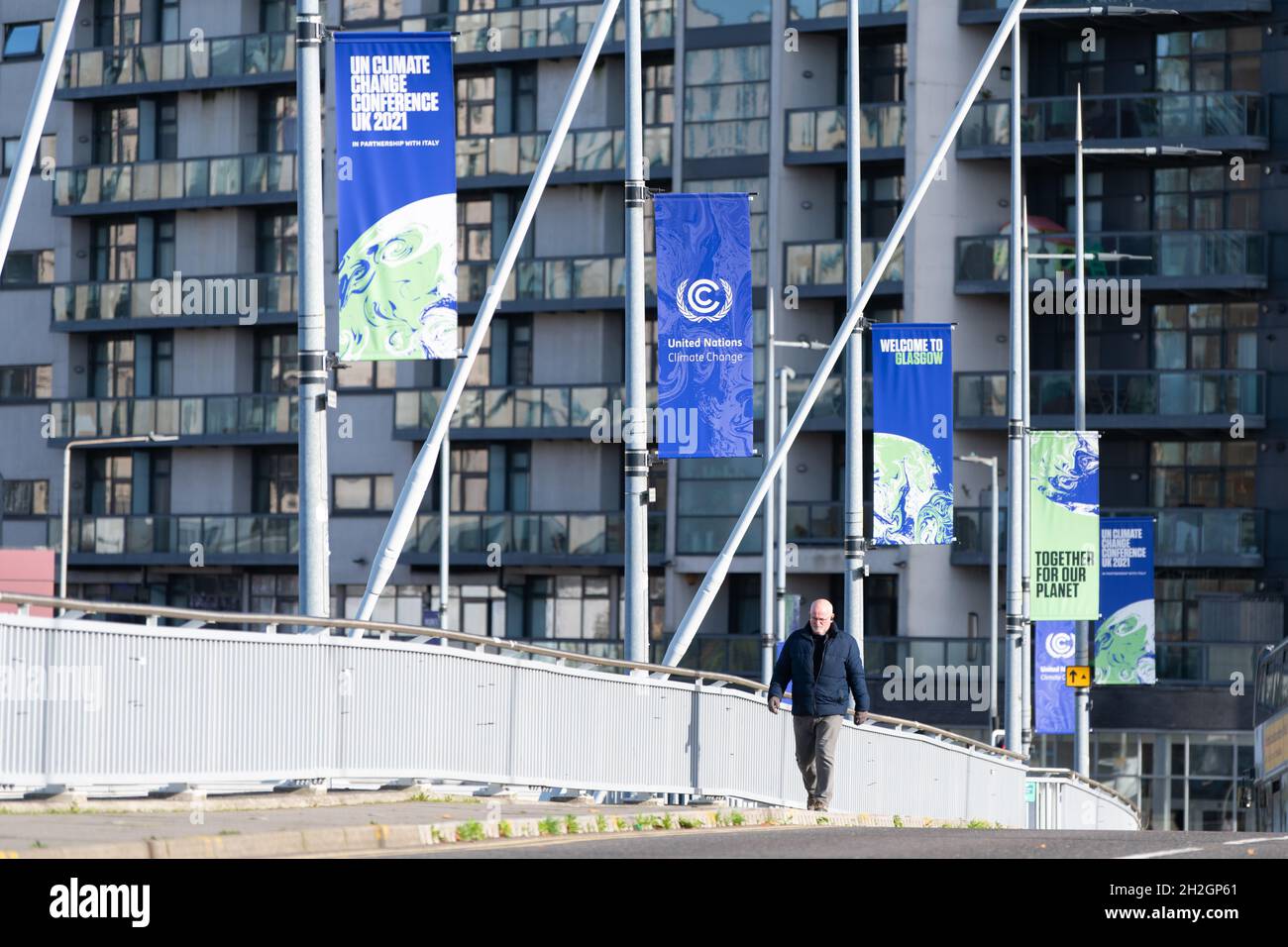 COP26 Glasgow - membro del pubblico che cammina sul ponte Clyde Arc sotto i banner delle Nazioni Unite sui cambiamenti climatici a Glasgow, Scozia, Regno Unito Foto Stock