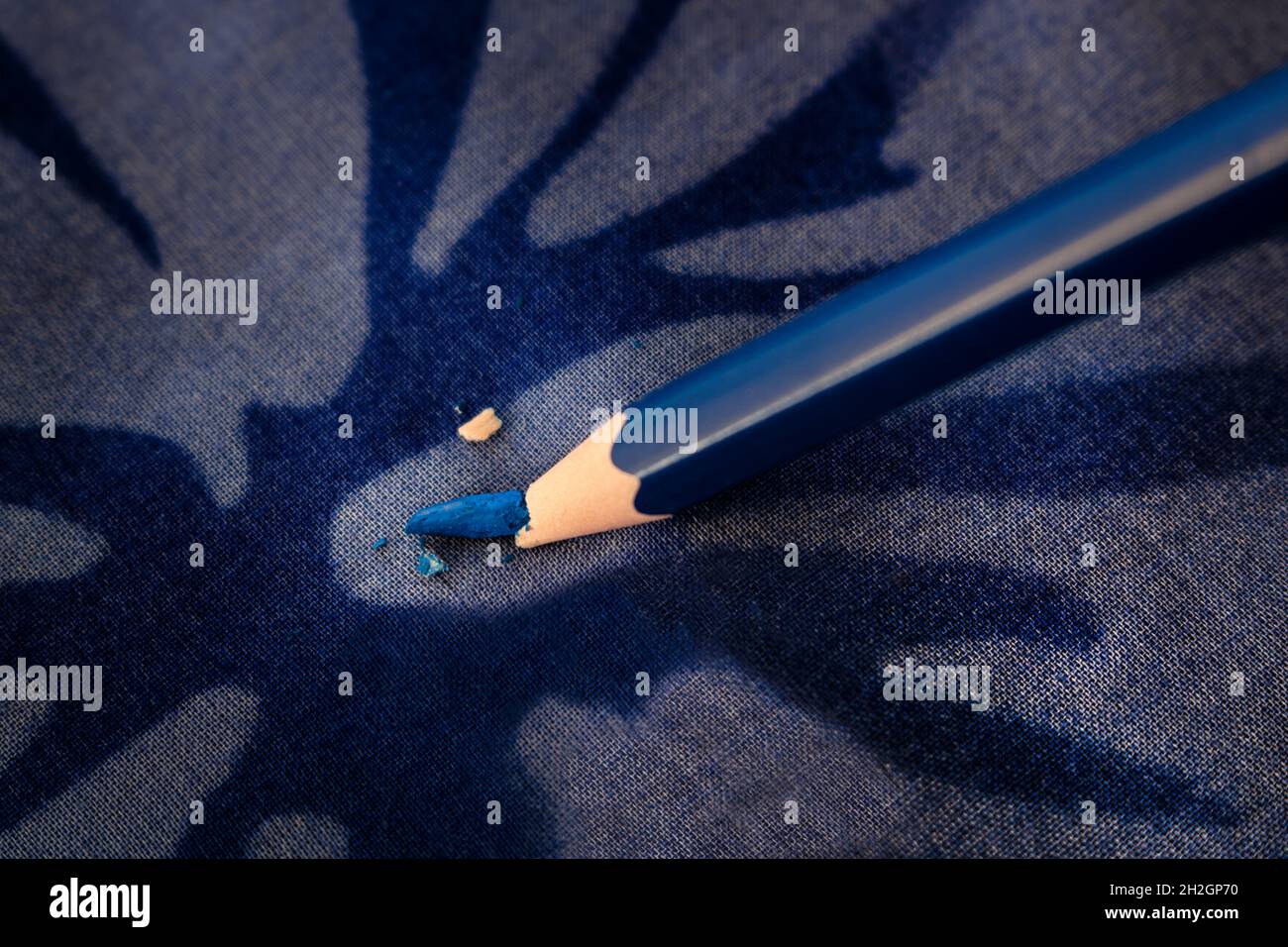 Primo piano di matita da colorare blu scuro con punta rotta contro una superficie dura con motivo blu astratto. Concetto di pressione o di blocco creativo Foto Stock