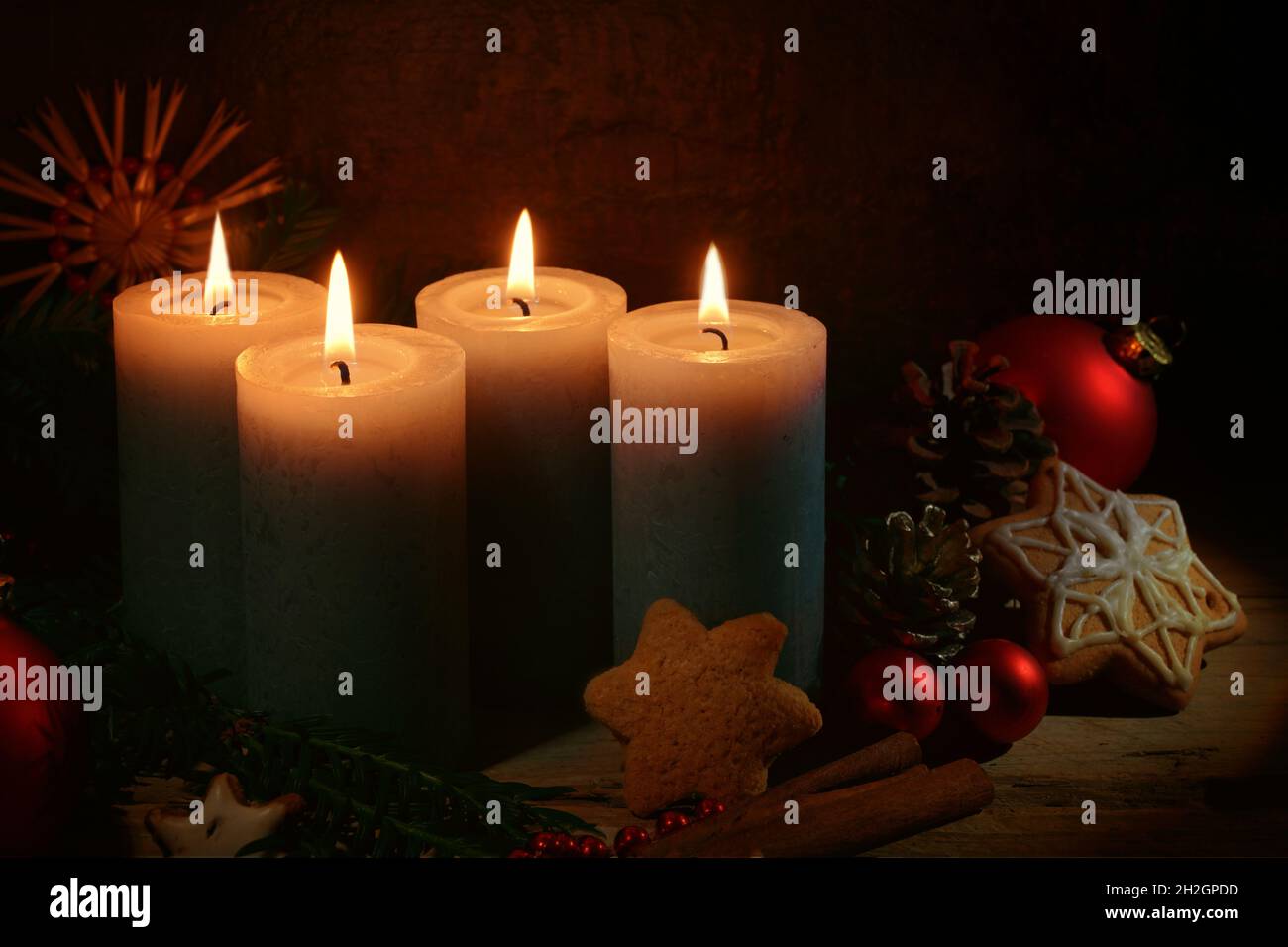 Quattro candele accese per l'avvento, decorazione di Natale e biscotti di pan di zenzero su uno sfondo rustico marrone scuro, spazio copia, fuoco selezionato, narr Foto Stock