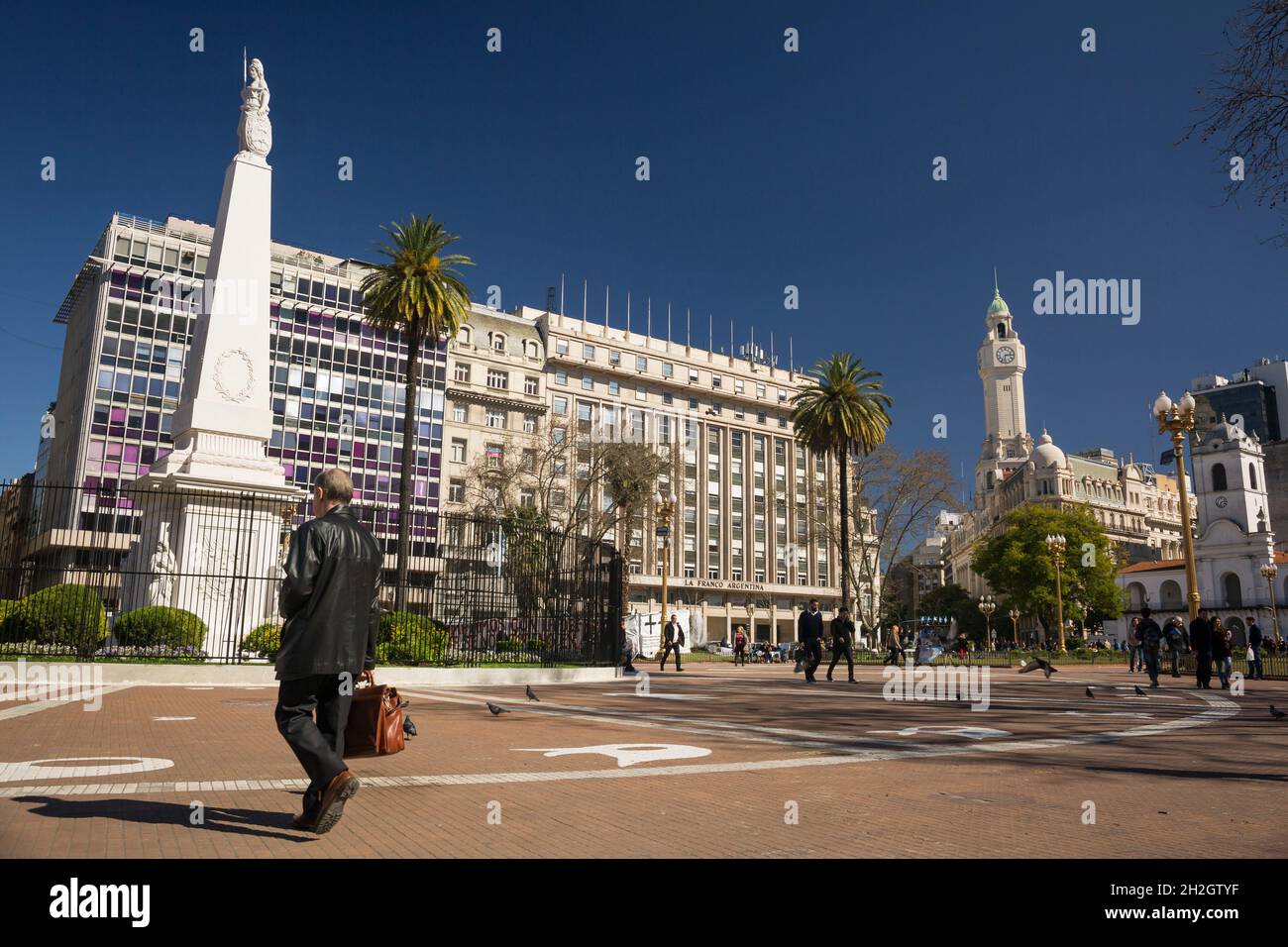 Vista panoramica di un uomo che attraversa Plaza de Mayo a Buenos Aires con il Pirámide de Mayo, il più antico monumento nazionale della città, sulla sinistra Foto Stock