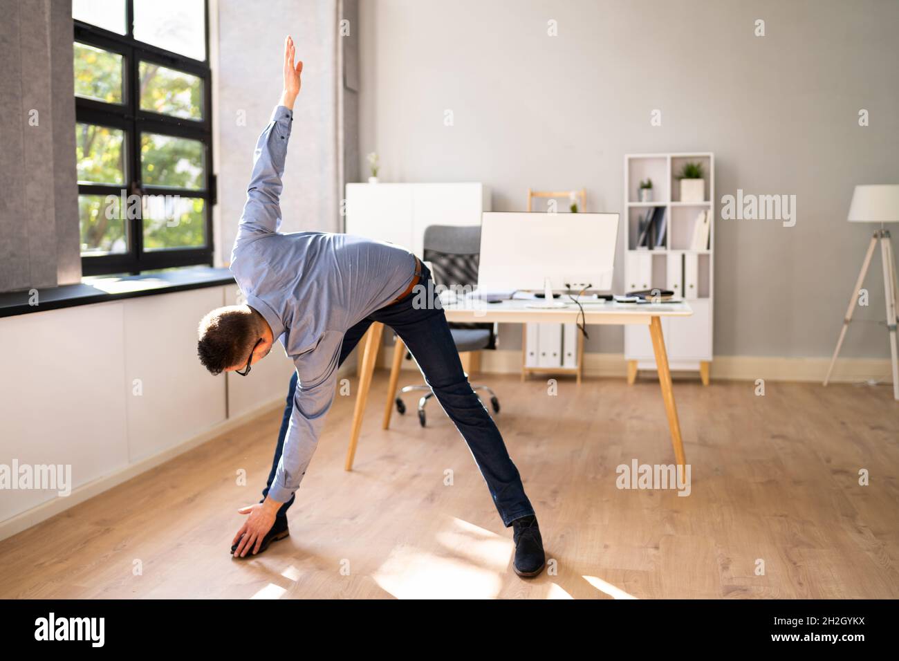 Braccio estensibile esercizio in piedi di fronte al computer Foto Stock