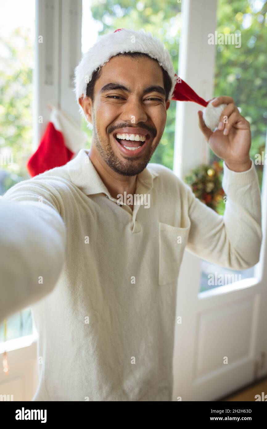 Ritratto di felice uomo biraciale in santa Hat fare videochiamata di natale Foto Stock