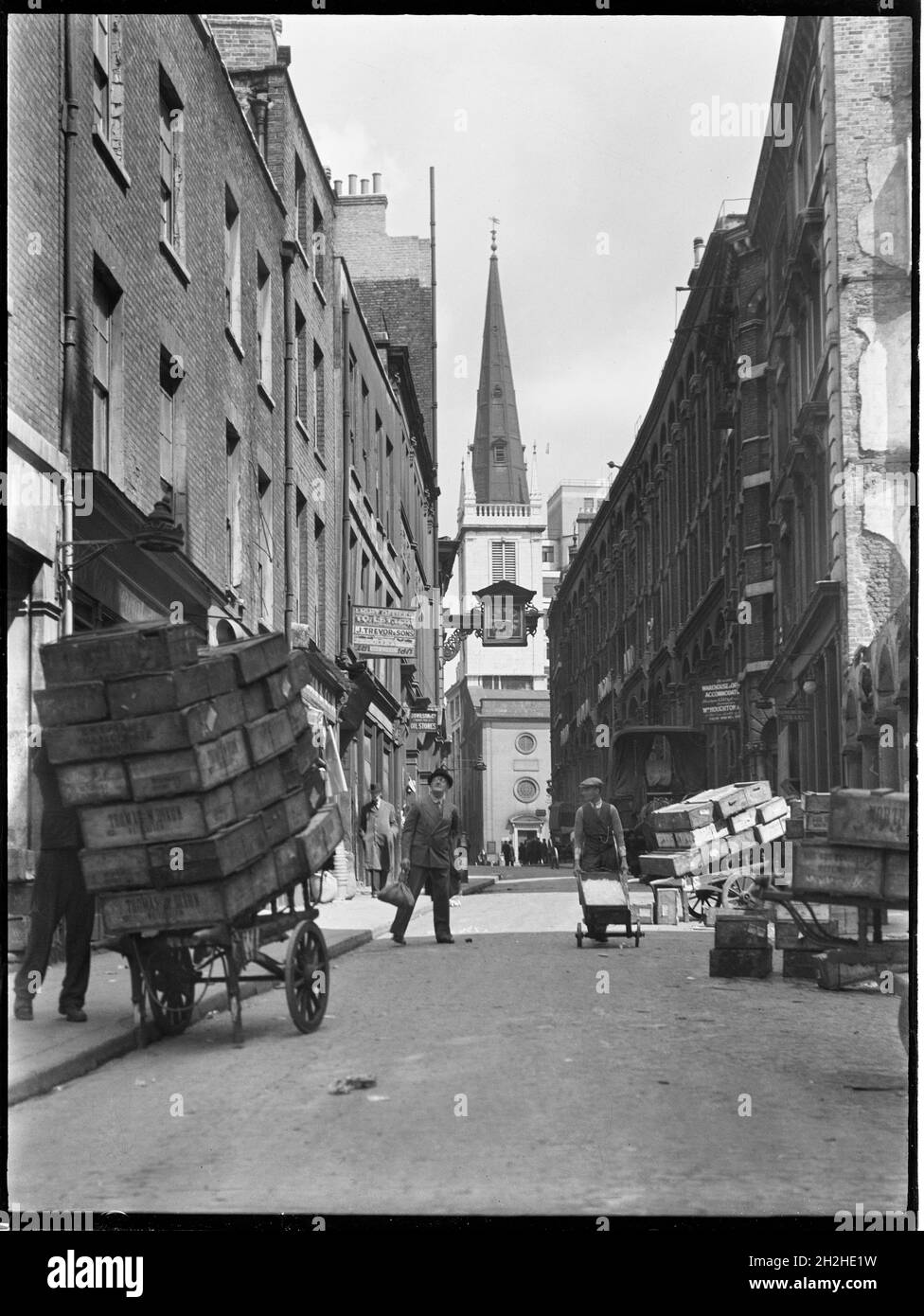 St Mary at Hill, City and County of the City of London, Greater London Authority, 1930. Una vista verso nord lungo St Mary at Hill verso la chiesa di St Margaret Pattens su Rood Lane, che mostra i carretti in primo piano carichi di casse. Con la sua vicinanza al Tamigi e al vecchio mercato del pesce di Billingsgate, gli edifici di St Mary at Hill erano occupati da un certo numero di venditori di pesci. Foto Stock
