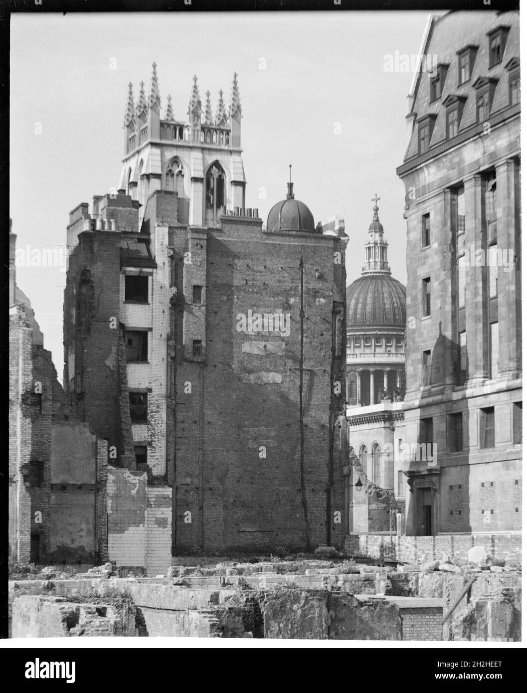 St Paul's Cathedral, St Paul's Churchyard, City of London, City and County of the City of London, Greater London Authority, 1941-1945. Una vista da nord-est che mostra la cupola della Cattedrale di San Paolo attraverso uno spazio tra gli edifici, con la cima della torre della Chiesa di San Albano su Wood Street dietro un edificio danneggiato dalla bomba in primo piano. La Chiesa di St Alban fu ricostruita da Christopher Wren dopo il Grande incendio di Londra nel 1666. Durante la seconda guerra mondiale fu distrutta dai bombardamenti con la sola torre sopravvissuta. Foto Stock