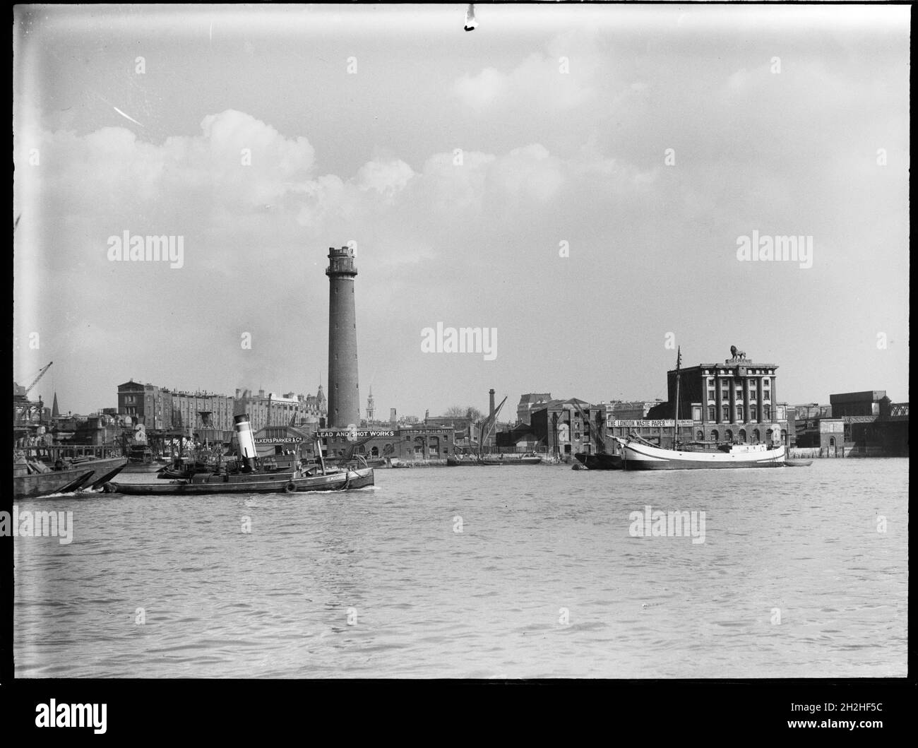 Shot Tower and Lead Works, Belvedere Road, Lambeth, Greater London Authority, 1936. Una vista sul Tamigi verso la torre dei colpi di Lambeth Lead Works con la Birreria Lion sulla destra. La torre di tiro dei Lambeth Lead Works fu progettata da David Ridall Roper e fu costruita nel 1826 per Thomas Maltby &amp; Co. Al tempo di questa fotografia fu gestita da Walkers, Parker &amp; Co, ma fu demolita nel 1962 per fare posto alla Sala della Regina Elisabetta. La Birreria Lion fu costruita nel 1836-37, ma fu demolita nel 1949 per far posto al Royal Festival Hall. Foto Stock