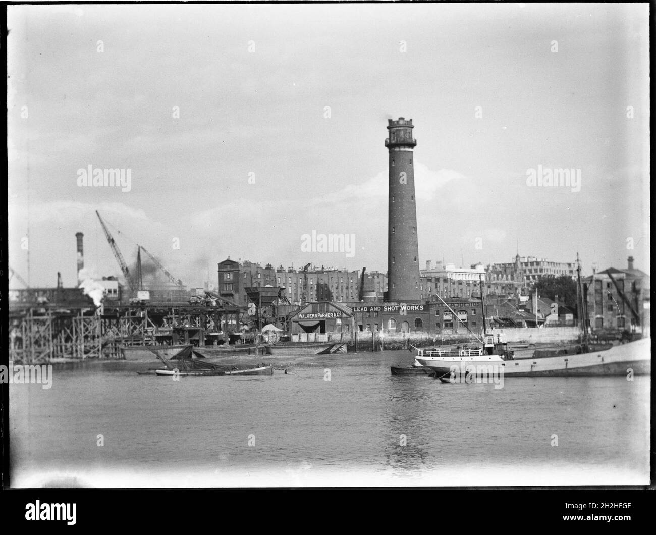 Shot Tower and Lead Works, Belvedere Road, Lambeth, Greater London Authority, 1936. Una vista sul Tamigi verso la torre dei colpi di Lambeth Lead Works, che mostra la demolizione del vecchio ponte Waterloo sulla sinistra. La torre di tiro dei Lambeth Lead Works fu progettata da David Ridall Roper e fu costruita nel 1826 per Thomas Maltby & Co. Al tempo di questa fotografia fu gestita da Walkers, Parker & Co, ma fu demolita nel 1962 per fare posto alla Sala della Regina Elisabetta. Il Waterloo Bridge, che viene mostrato durante la sua demolizione, è stato progettato da John Rennie e aperto Foto Stock