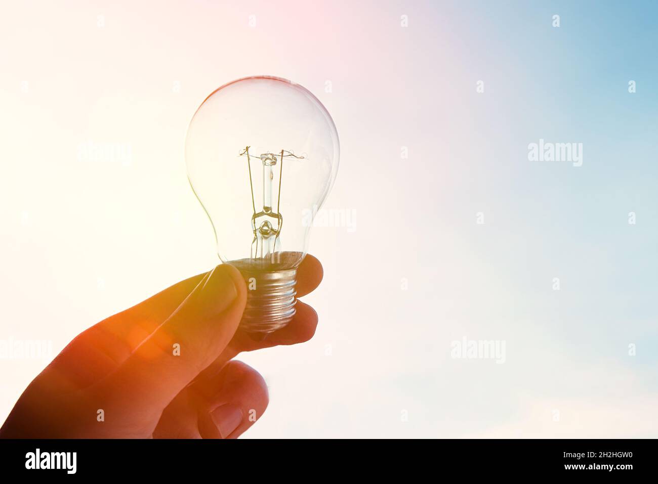 Concetto di crisi energetica globale. L'uomo tiene la lampadina in alto Foto Stock