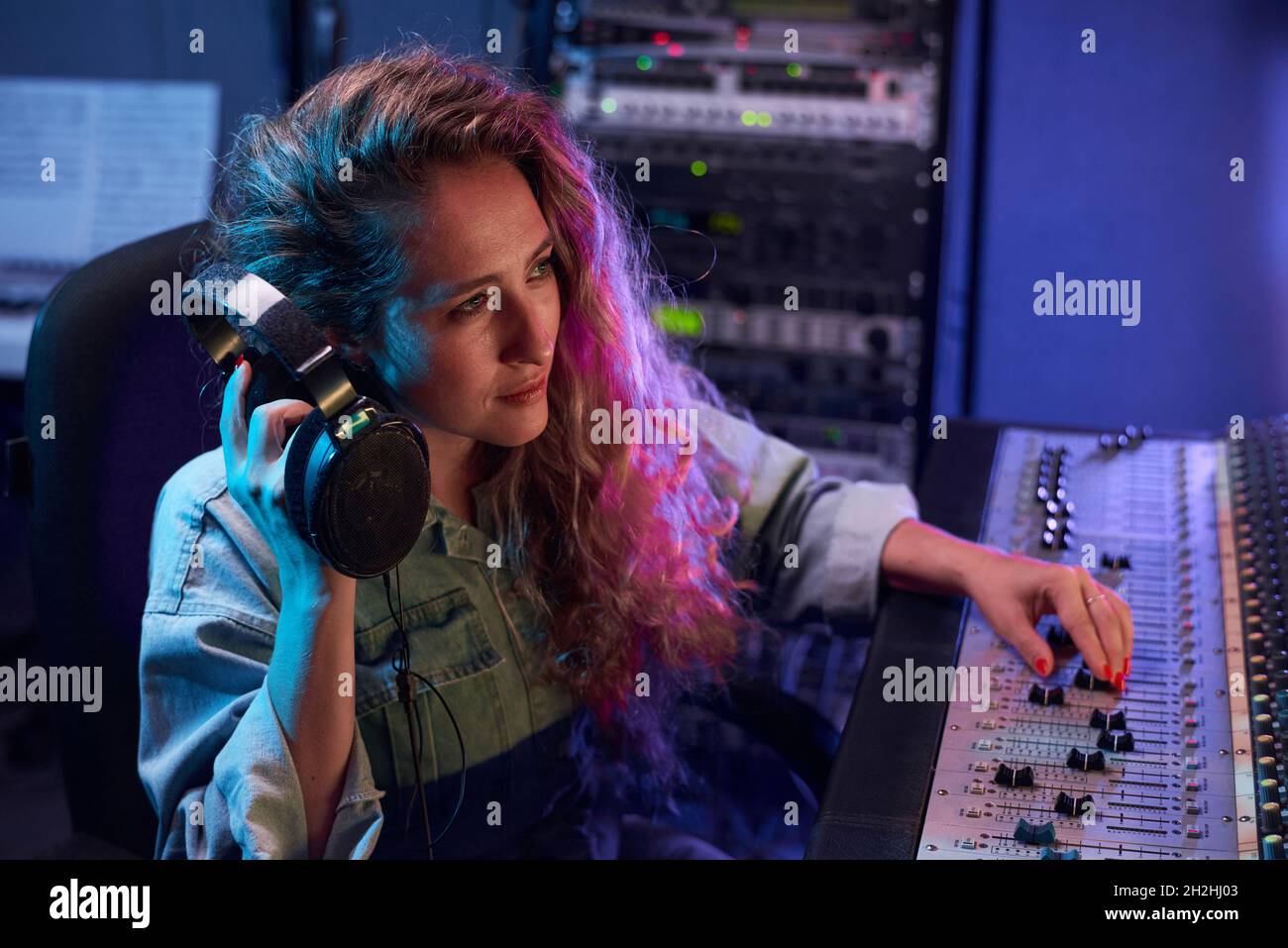 Primo piano di cuffie giovani donne con tastiera elettronica mentre si lavora in studio di registrazione digitale Foto Stock