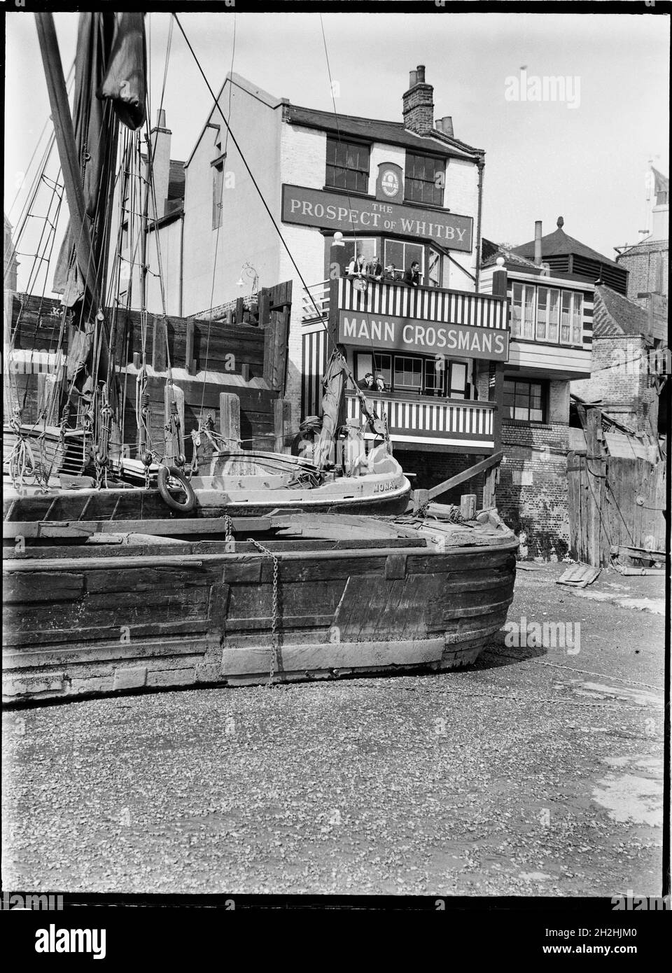 Prospettiva di Whitby, Wapping Wall, Wapping, Tower Hamlets, Greater London Authority, anni '30. L'elevazione del fiume del Prospect of Whitby pub visto da sud sulla riva del fiume a Wapping, mostrando gli uomini sui suoi balconi con vista sul fiume e chiatte in primo piano. Il Prospect of Whitby Public House risale al 1520 circa ed è il pub più antico di Londra lungo il fiume. Foto Stock