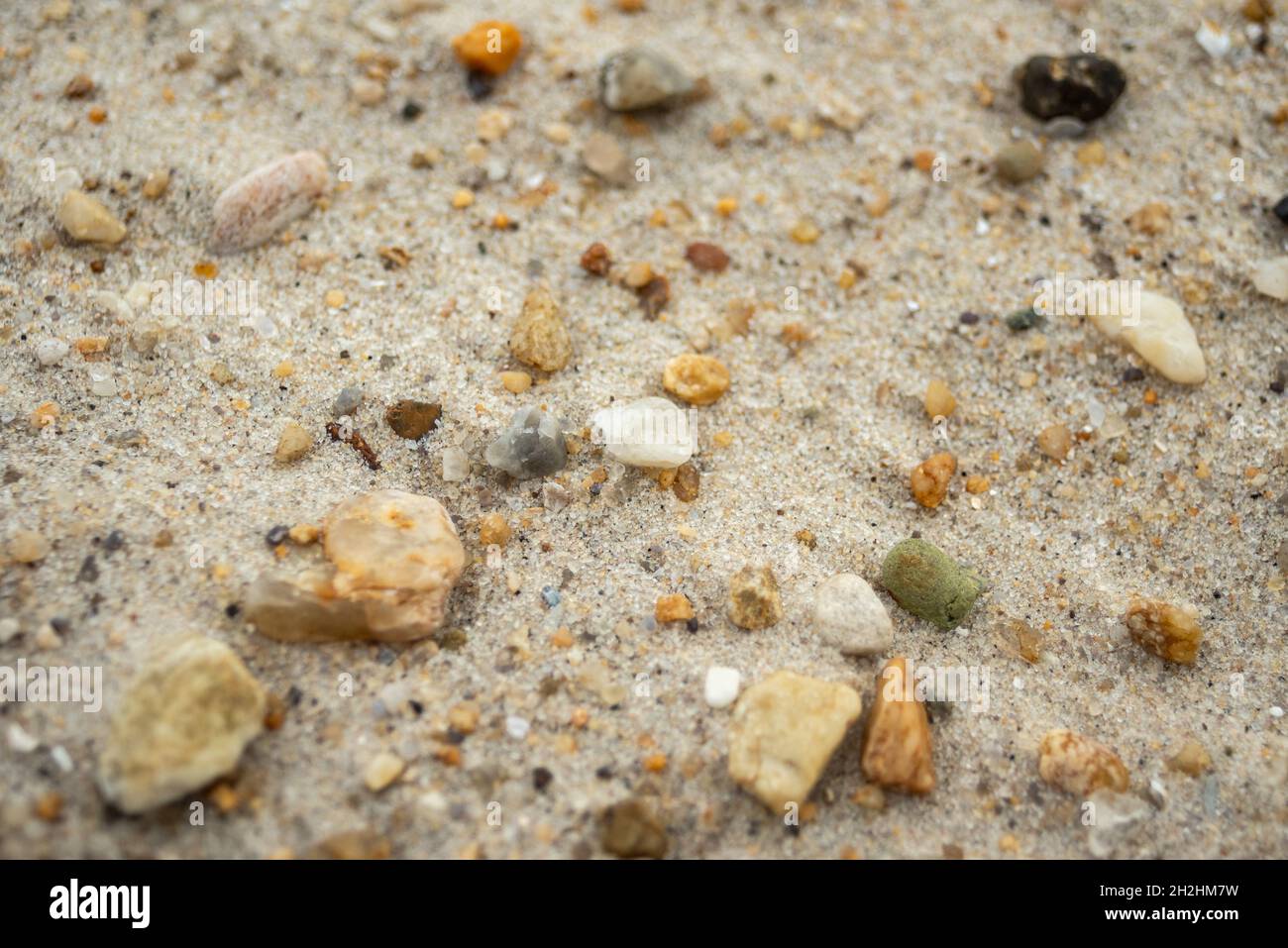Ciottoli con una varietà di forme e colori interlacciati con sabbia da spiaggia Foto Stock