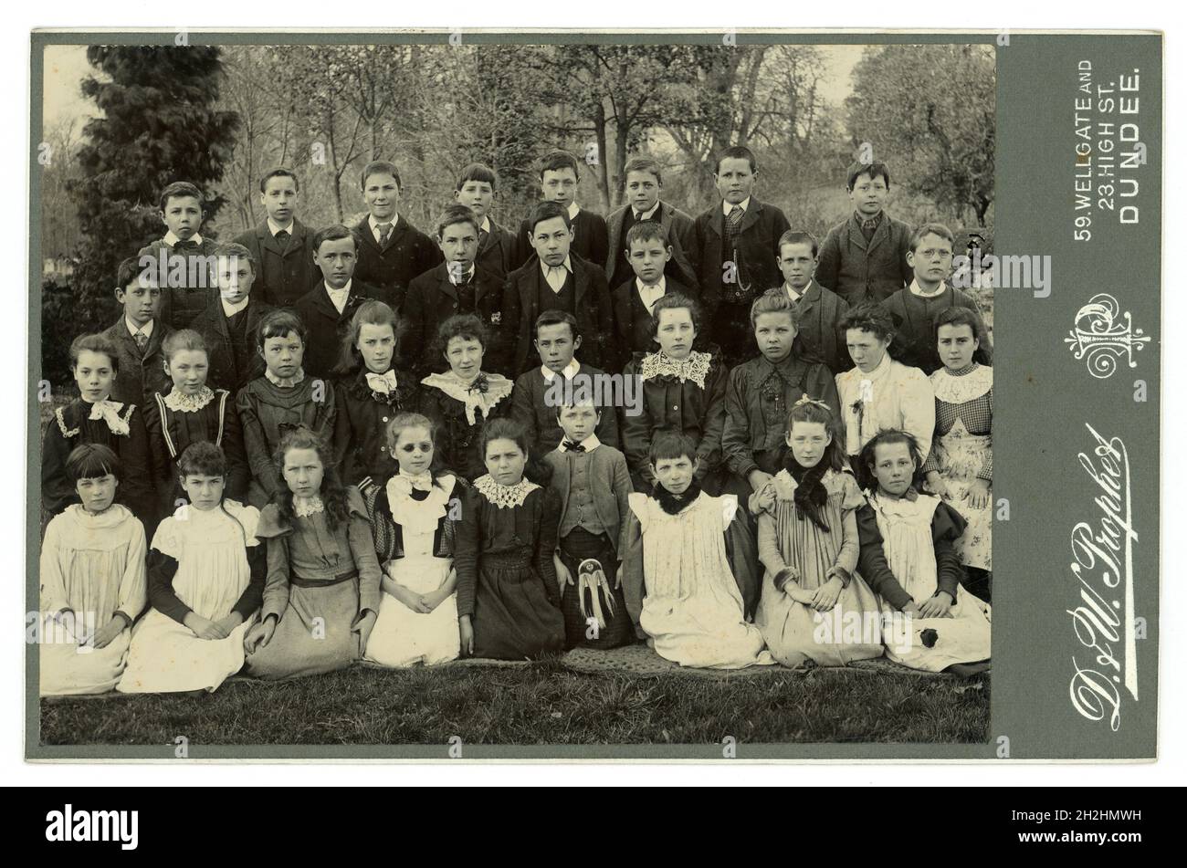 Carta originale e trasparente per il cabinet vittoriano di un gruppo di bambini delle scuole vittoriane, di classe vittoriana, ragazzi e ragazze, di classe media e ben vestiti e uno dei ragazzi indossa un orologio da tasca che era costoso all'epoca. Posa per un ritratto di gruppo all'aperto. Molti abiti meravigliosi dall'inizio alla fine degli anni '1890 - abiti in fumetto e stili a maniche piene dal 1893 al 98, dallo studio di D. & W. Prophet, Dundee, Scozia, Regno Unito foto scattata intorno al 1898 Foto Stock