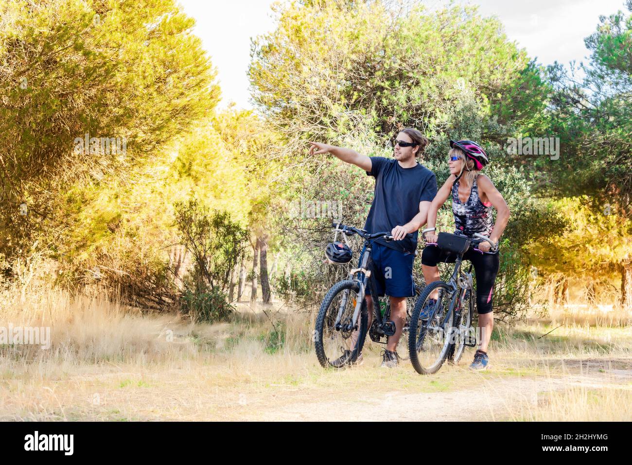 Due ciclisti, un uomo e una donna, in piedi con le loro biciclette in mezzo alla campagna. Il ciclista maschio punta con il dito alla femmina Foto Stock