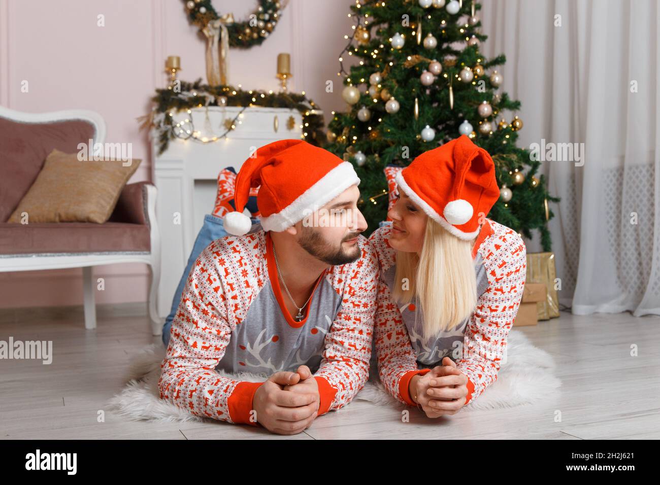 Bella coppia felice nel paesaggio di Natale. Weared in maglioni e cappelli  divertenti. Distendersi a terra e divertirsi Foto stock - Alamy