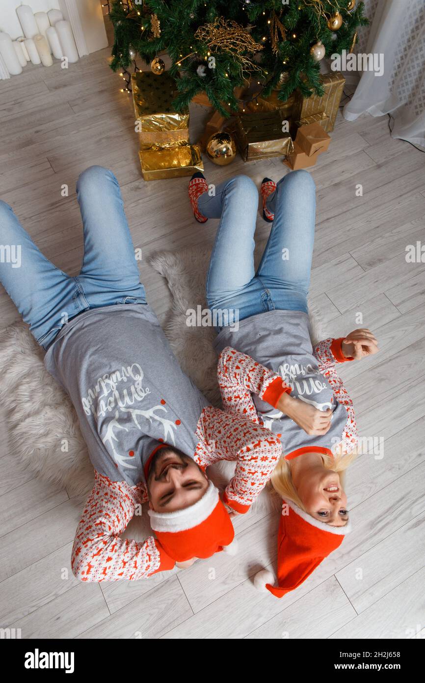 Bella coppia felice nel paesaggio di Natale. Weared in maglioni e cappelli  divertenti. Distendersi a terra e divertirsi Foto stock - Alamy
