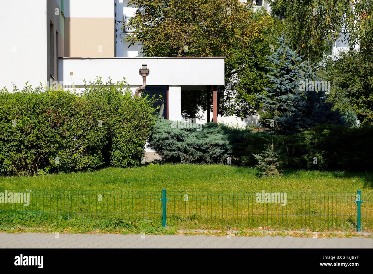 Piante lussureggianti e ornamentali crescono vicino al vestibolo di un edificio di appartamenti nel quartiere residenziale di Goclaw a Varsavia. Foto Stock