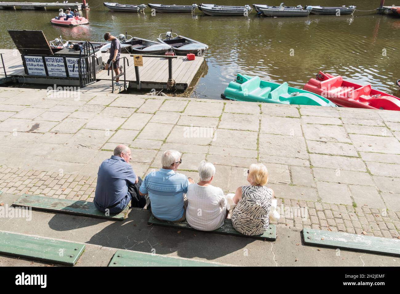 Persone sedute che parlano e guardano l'attività della barca sul fiume Dee Chester 2021 Foto Stock