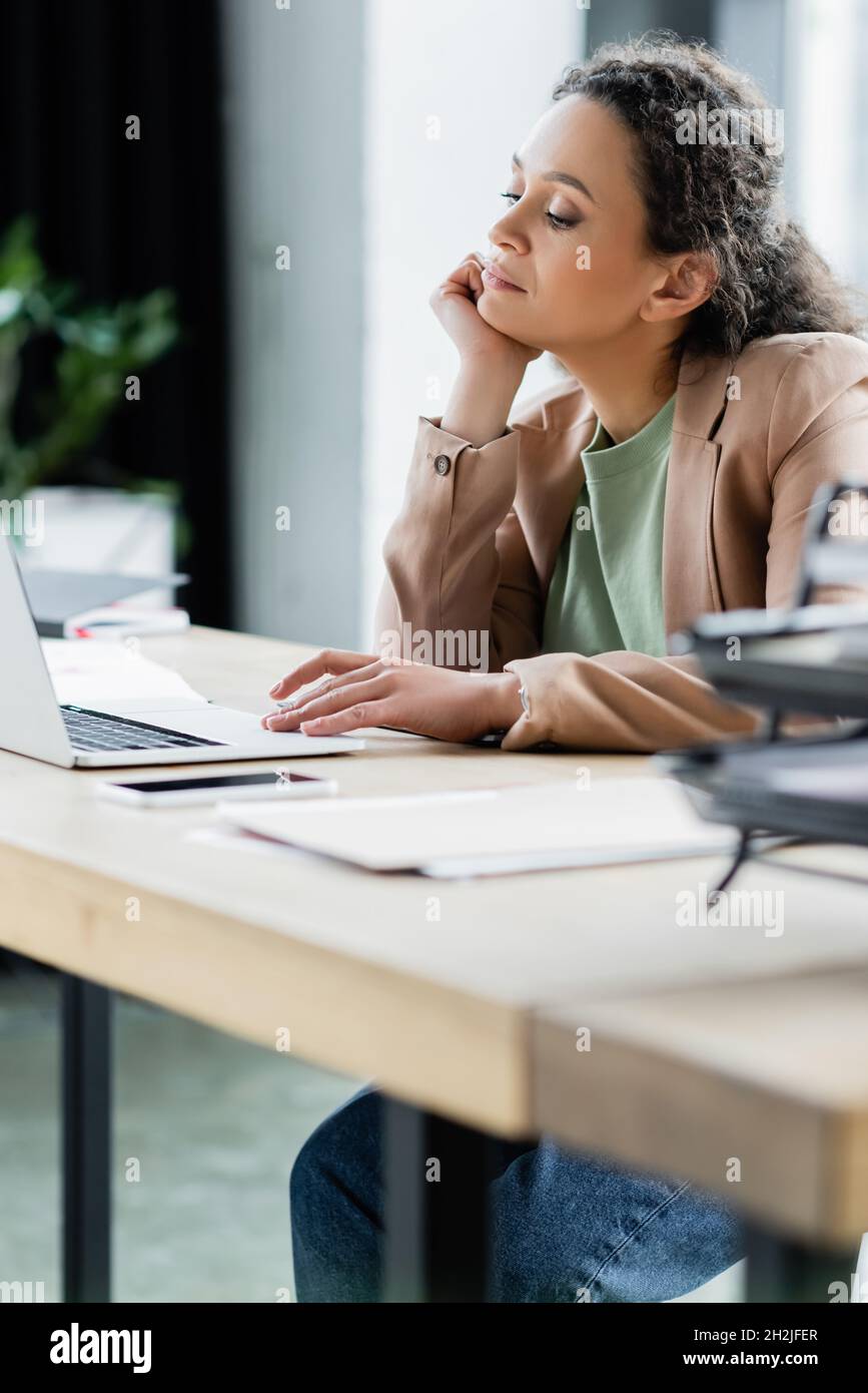 donna d'affari afroamericana pensata seduto sul posto di lavoro vicino a un computer portatile Foto Stock
