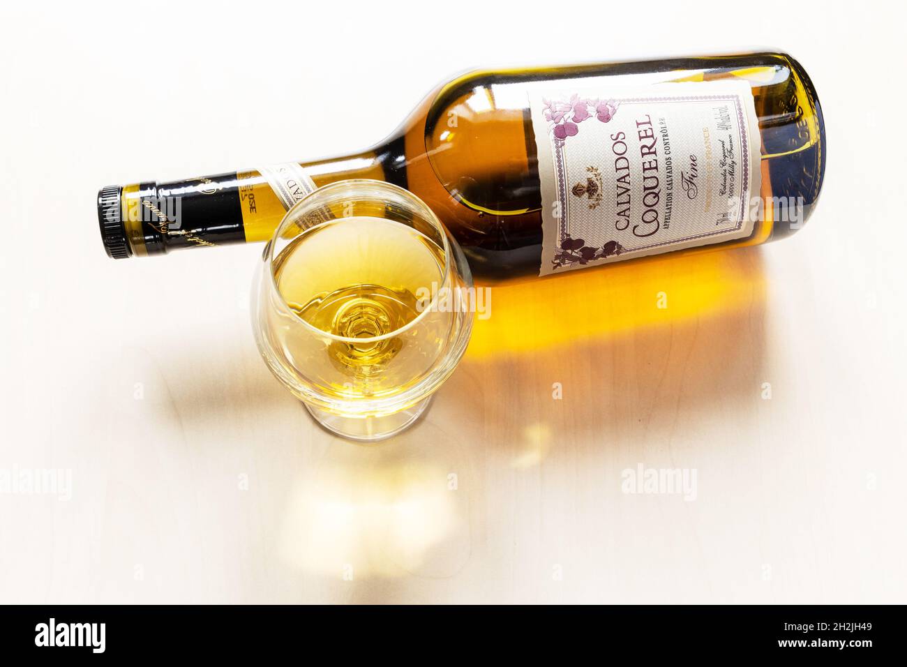 Mosca, Russia - 30 settembre 2021: wineglass e bottiglia di giacitura con francese Coquerel Calvados fine su tavolo marrone chiaro. Coquerel calvados è stato fondato Foto Stock