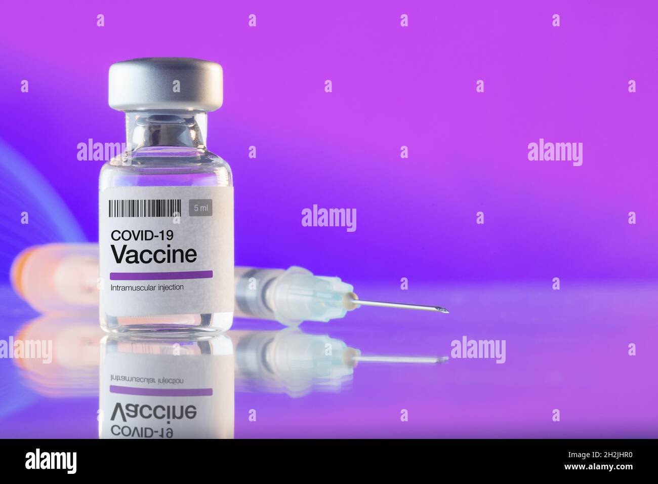 Primo piano di un flaconcino con vaccino e siringa COVID-19 su sfondo viola. Vaccinazioni, Covid-19, industria farmaceutica e concetti di salute Foto Stock