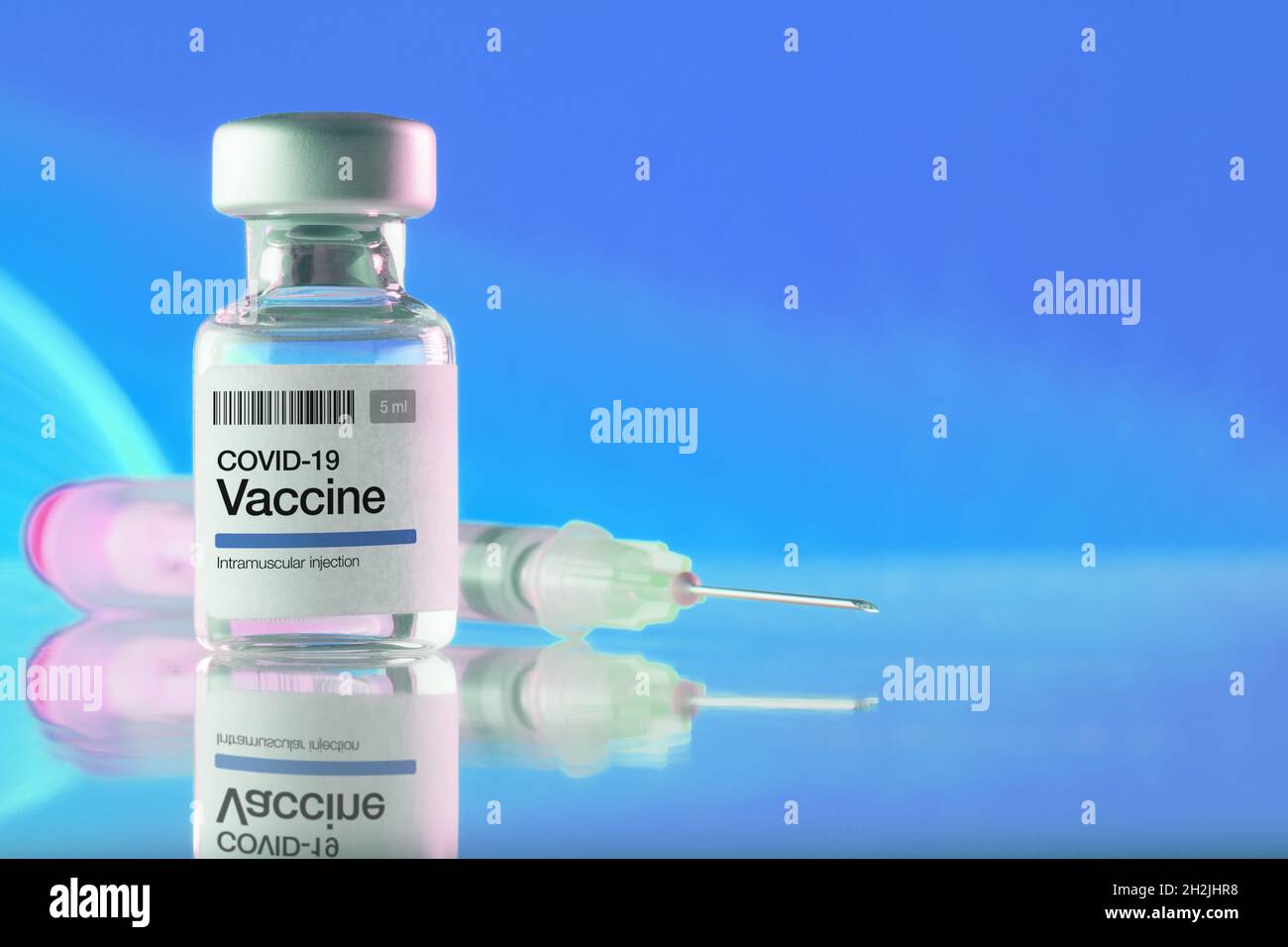 Primo piano di un flaconcino con vaccino e siringa COVID-19 su sfondo blu. Vaccinazioni, Covid-19, industria farmaceutica e concetti di salute Foto Stock