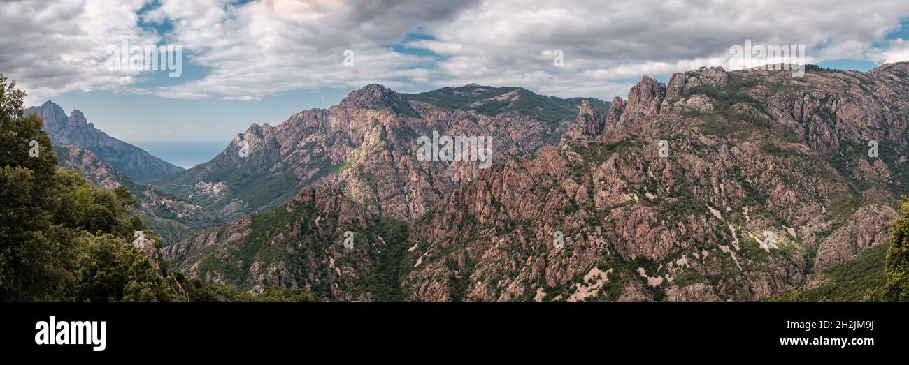 Vista panoramica sulle montagne rocciose della Corsica centrale con il villaggio di Ota e il mare Mediterraneo in lontananza Foto Stock
