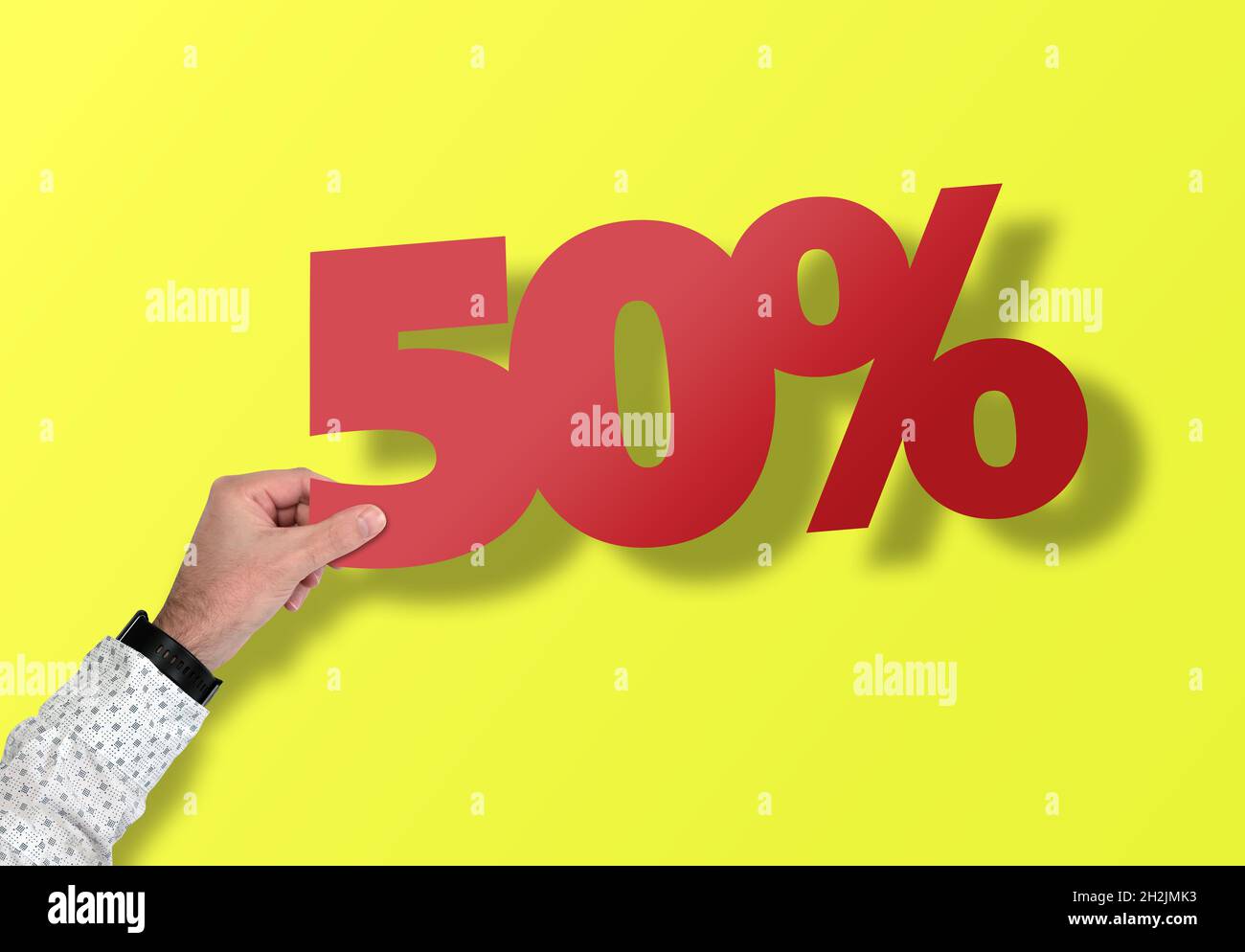 mano che tiene rosso 50 segno di percento contro sfondo giallo, sconto e concetto di vendita Foto Stock