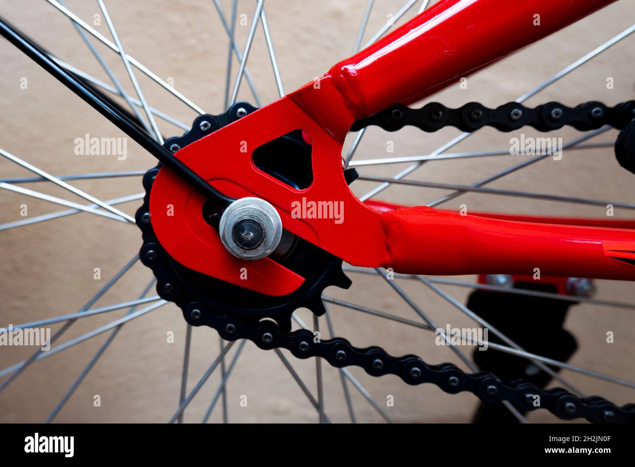 una vista ravvicinata della struttura rossa di ingranaggio, catena e raggi della bicicletta Foto Stock