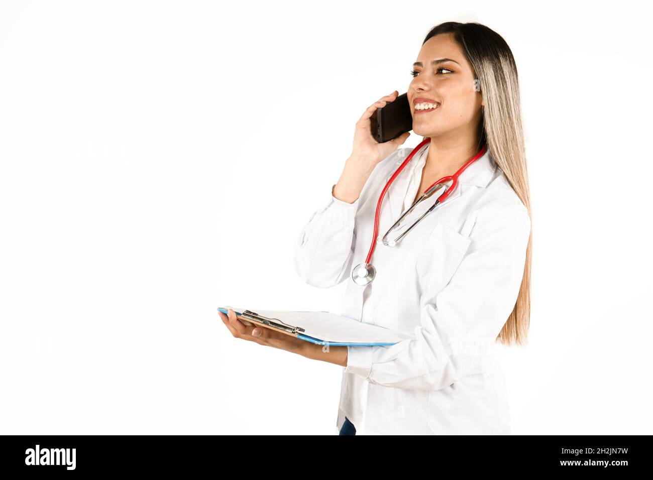 Una giovane dottoressa che parla al telefono cellulare e comunica buone notizie con una storia medica in mano. Concetto di donna professionale, personale lui Foto Stock