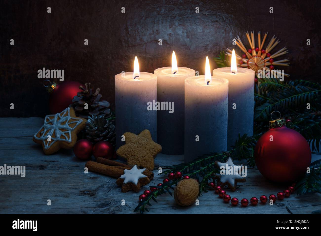Quattro candele di Avvento con decorazione natalizia, baubles e biscotti su tavole rustiche di legno su sfondo blu scuro con spazio copia, selezionato fo Foto Stock