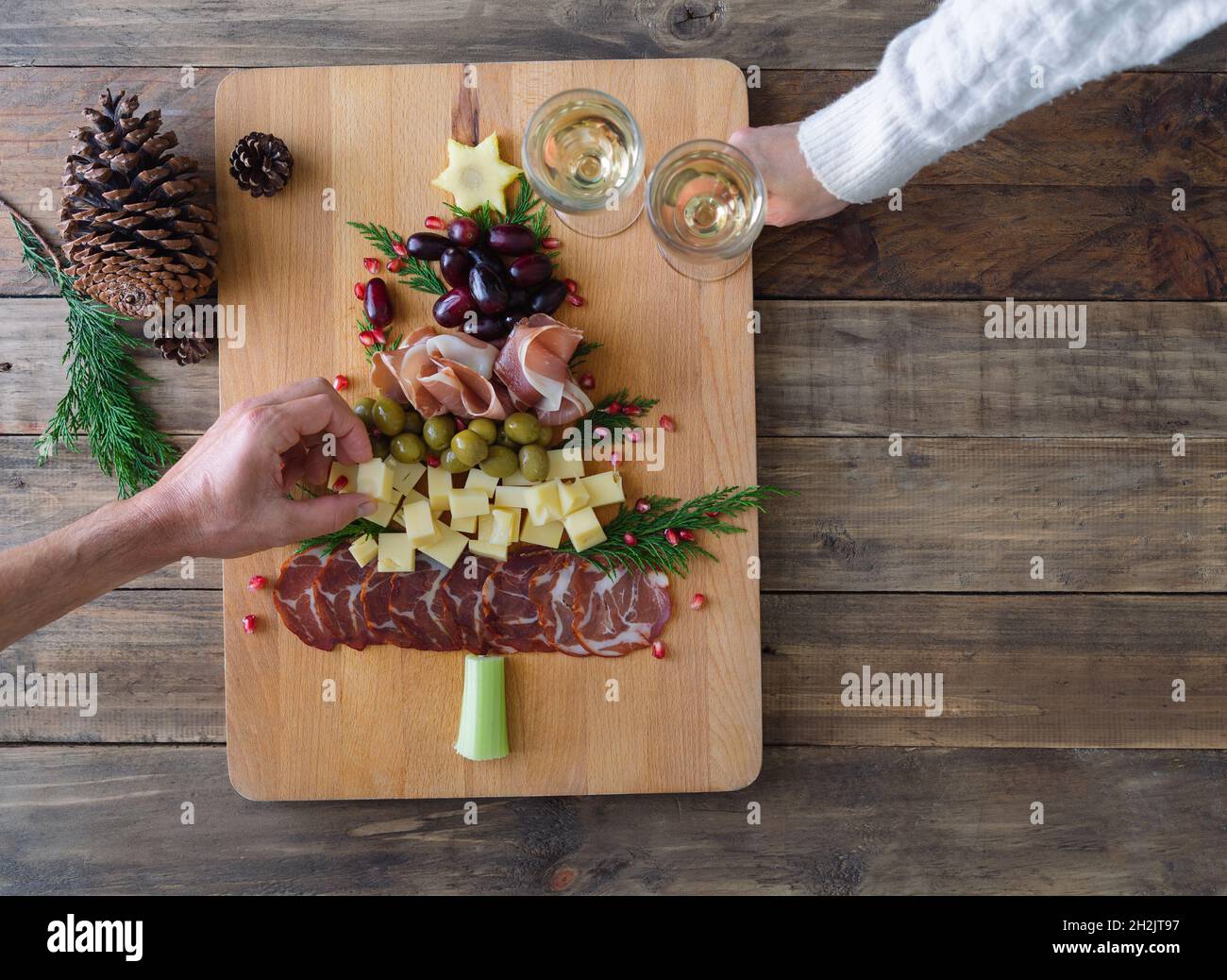 Formaggi e salumi a forma di albero di Natale. Due persone che mangiano.  Spazio di copia. Vista dall'alto Foto stock - Alamy