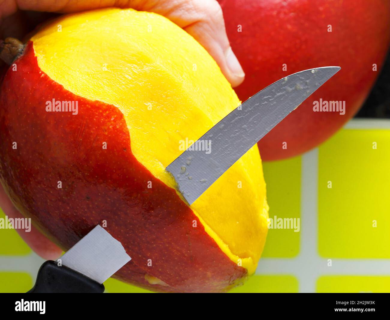 mango è preparato a mangiare. Il coltello sbuccia la frutta. Cibo sano Foto Stock