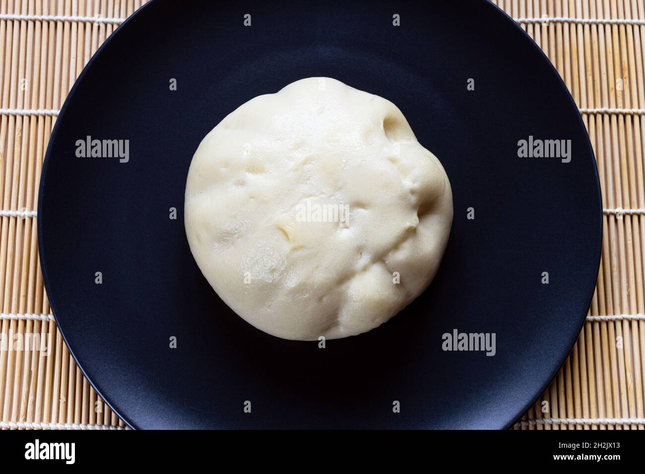Vista dall'alto di Banh bao al vapore, boccale salato vietnamita, su piatto nero Foto Stock