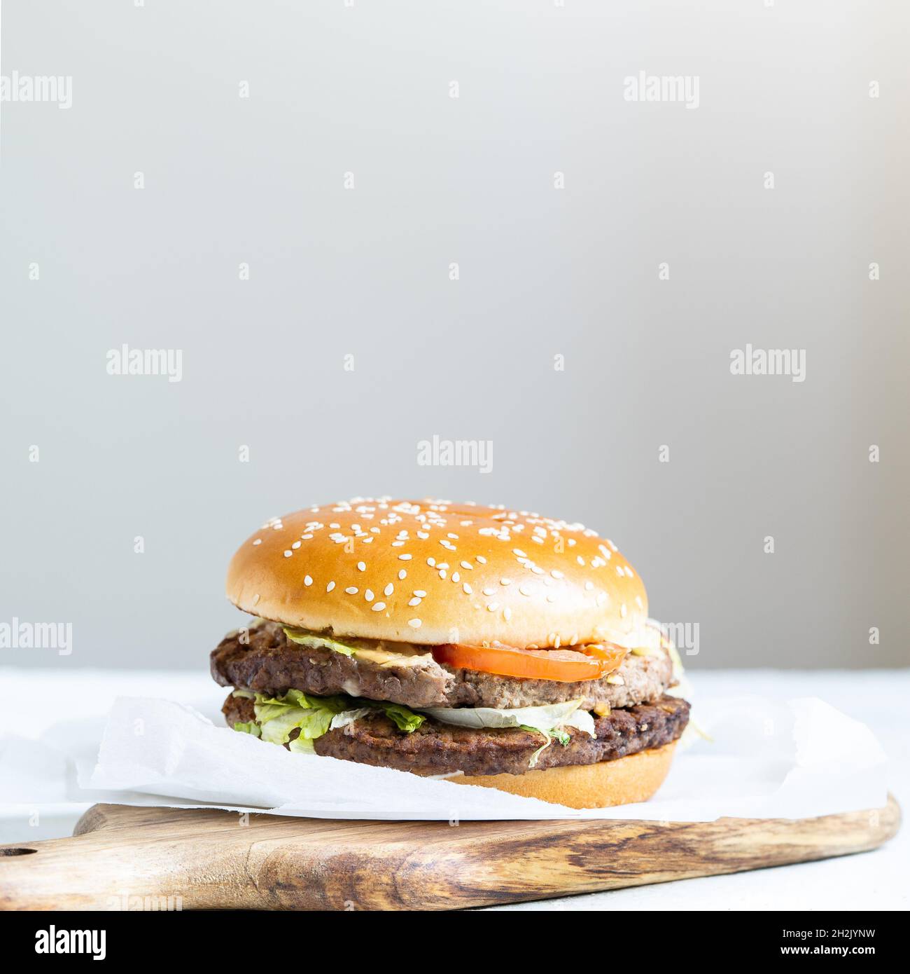 Cheeseburger doppio con cotolette di vitello, pomodori, foglie di lattuga e cetrioli. Fast food. Foto Stock