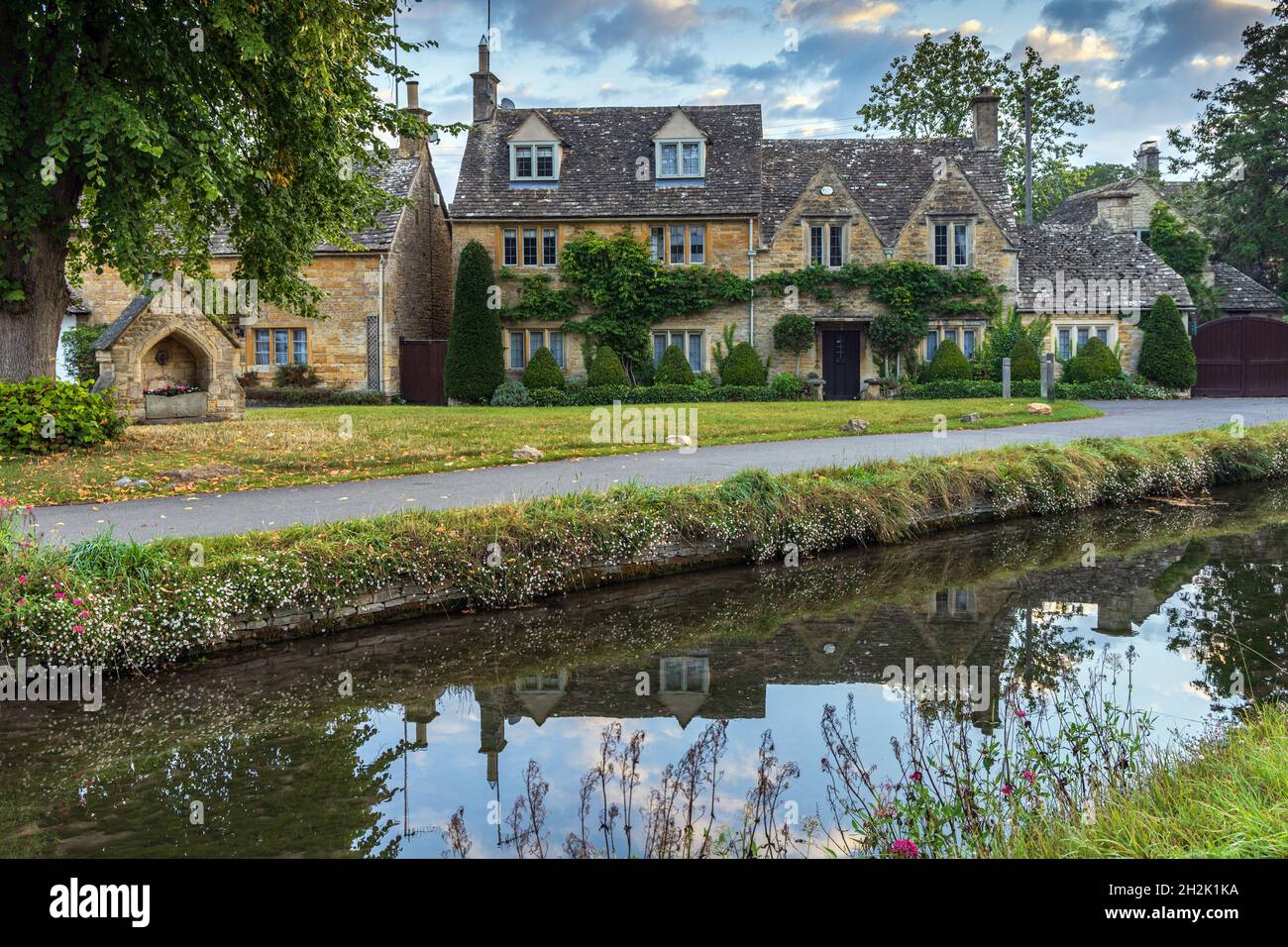 Cottage calcarei accanto al River Eye nel pittoresco villaggio di Cotswold di macellazione inferiore in Gloucestershire, Inghilterra. Foto Stock