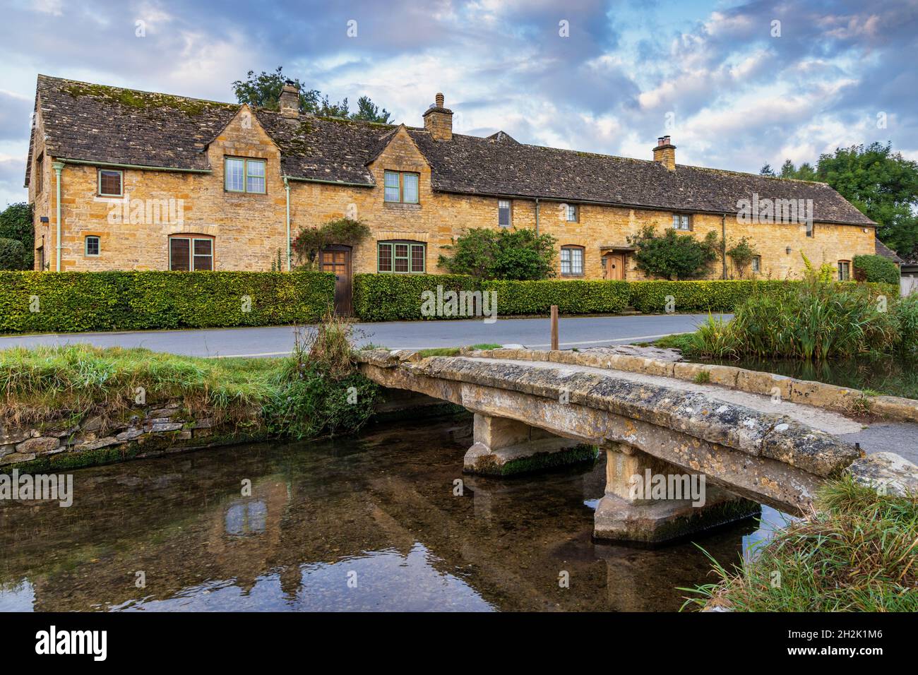 Passerella in pietra che attraversa il River Eye nel pittoresco villaggio di Cotswold di Lower Slaughter in Gloucestershire, Inghilterra. Foto Stock