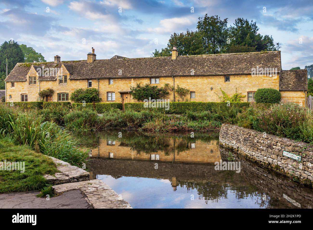 Cottage calcarei accanto al River Eye nel pittoresco villaggio di Cotswold di macellazione inferiore in Gloucestershire, Inghilterra. Foto Stock